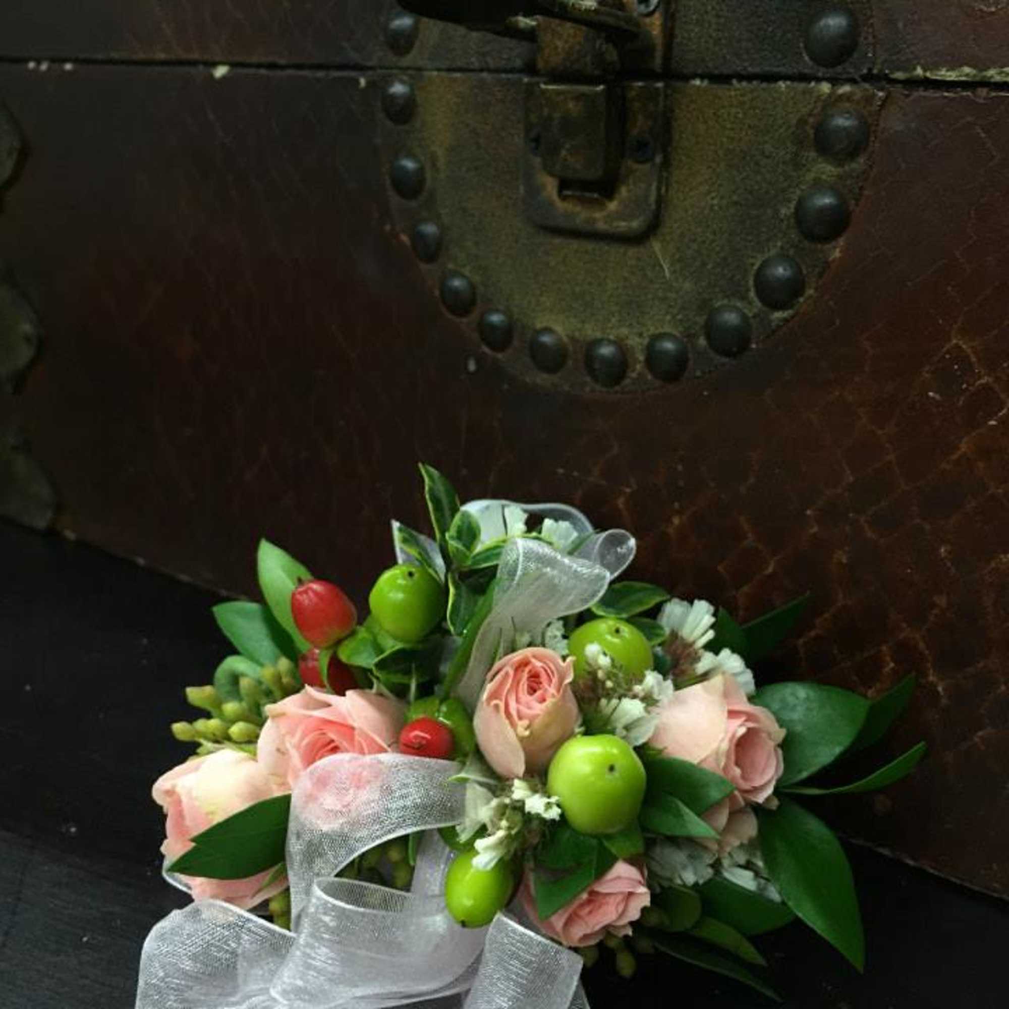 Pink rose bouquet with green berries and a white ribbon