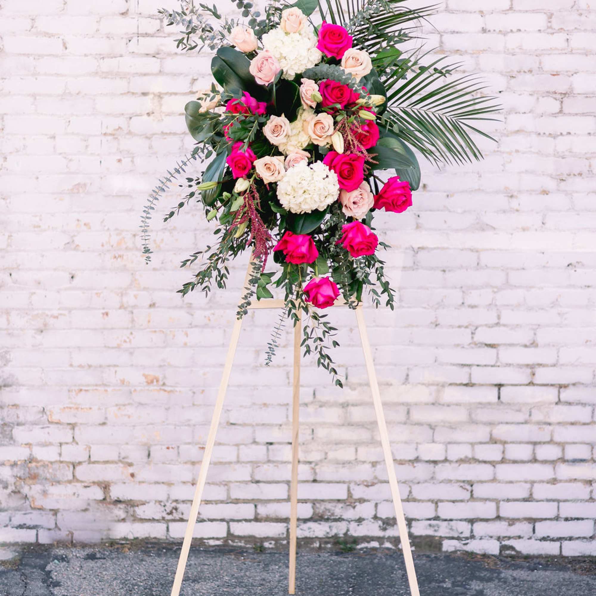 Standing floral spray with pink and white roses on a wooden easel