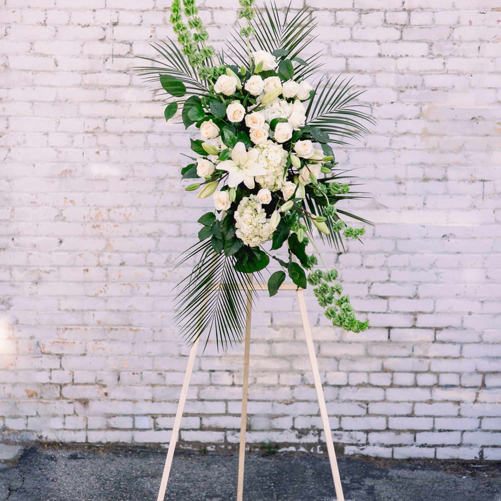 Tall white floral standing spray on a wooden easel