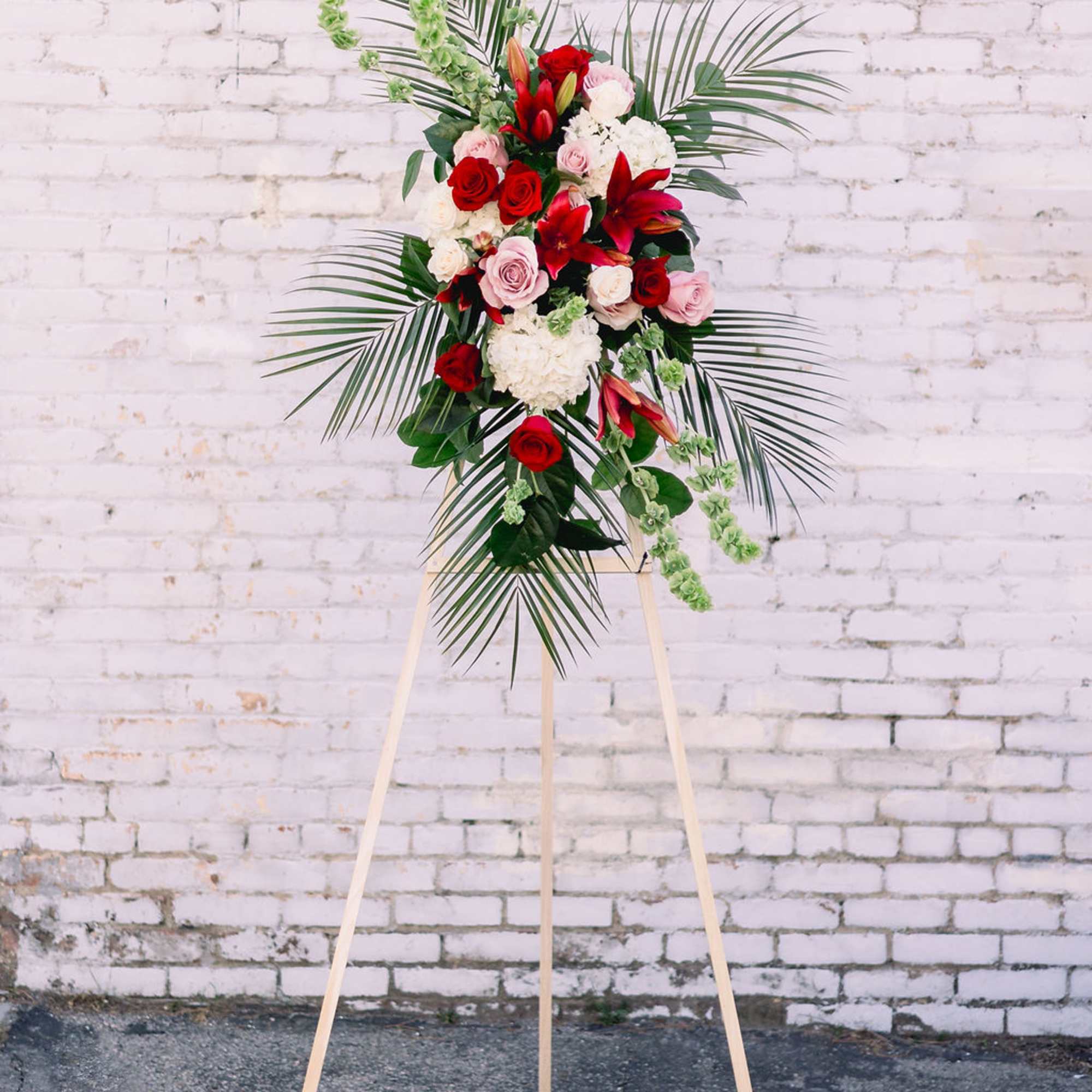 Standing floral spray with red and pink roses and lilies on an easel, photo 2 of 2