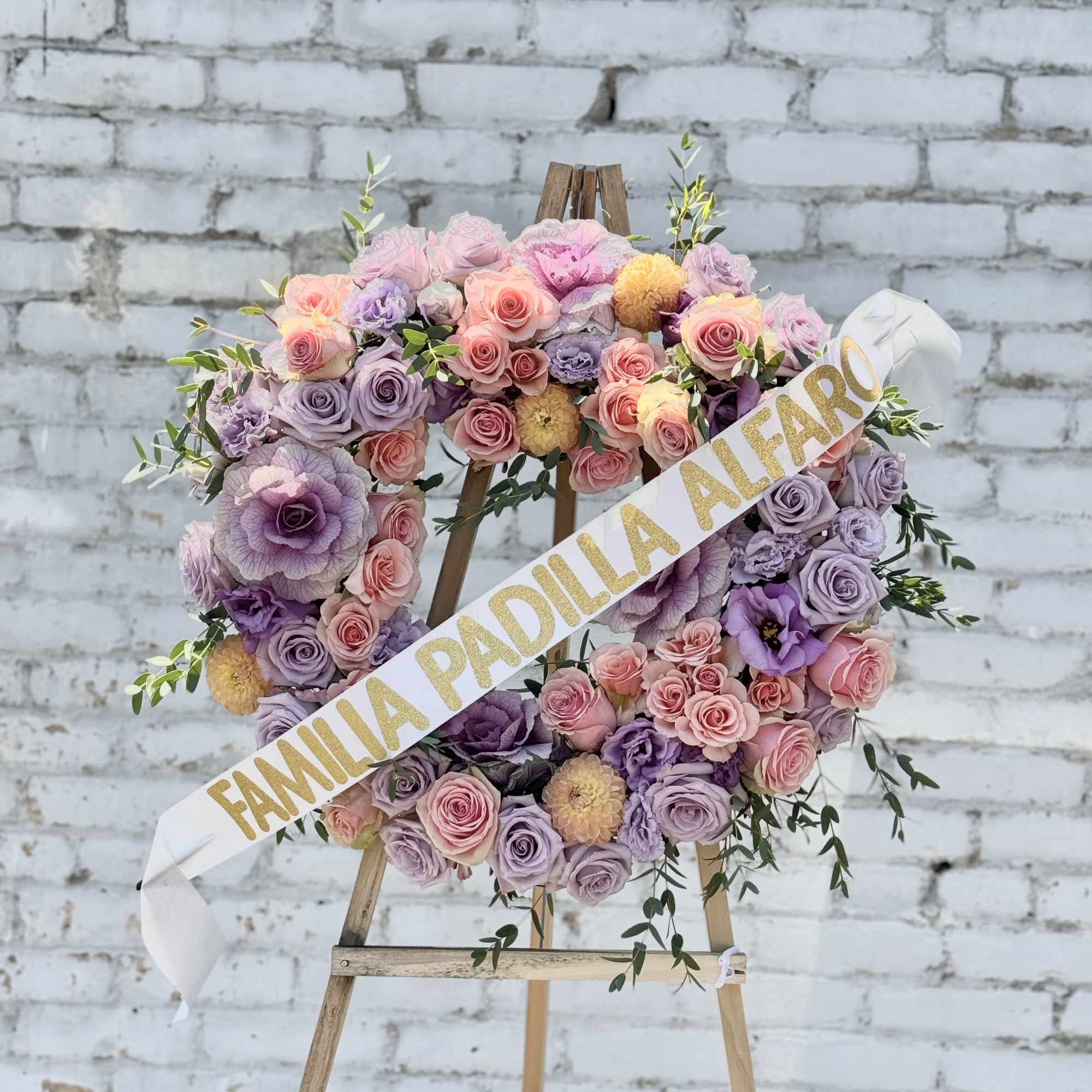 Pastel floral wreath on an easel with a name sash
