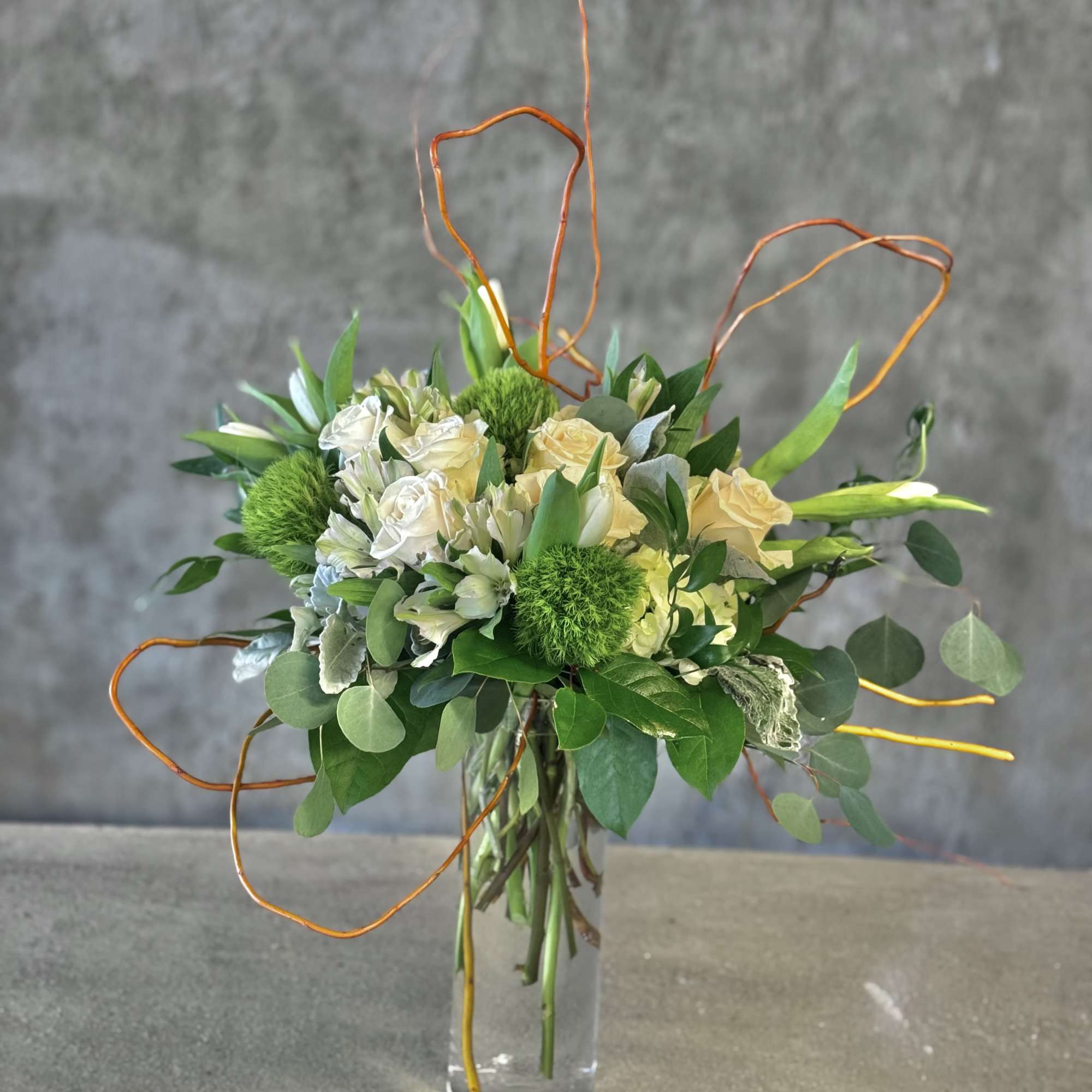 Bouquet of cream roses and green blooms in a clear glass vase