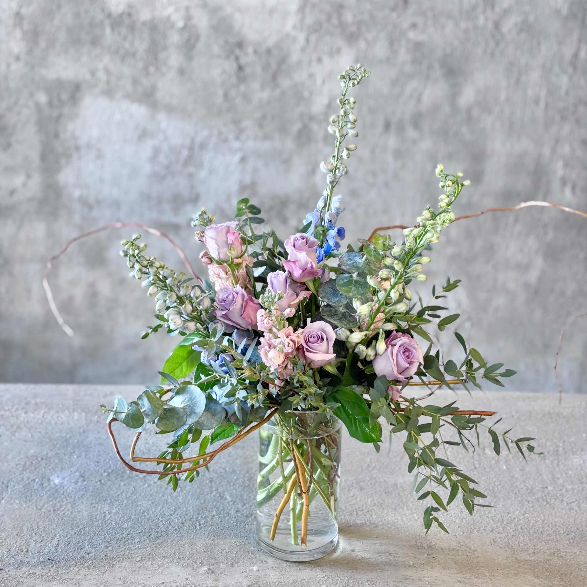 Lavender roses in a clear glass vase with airy greenery
