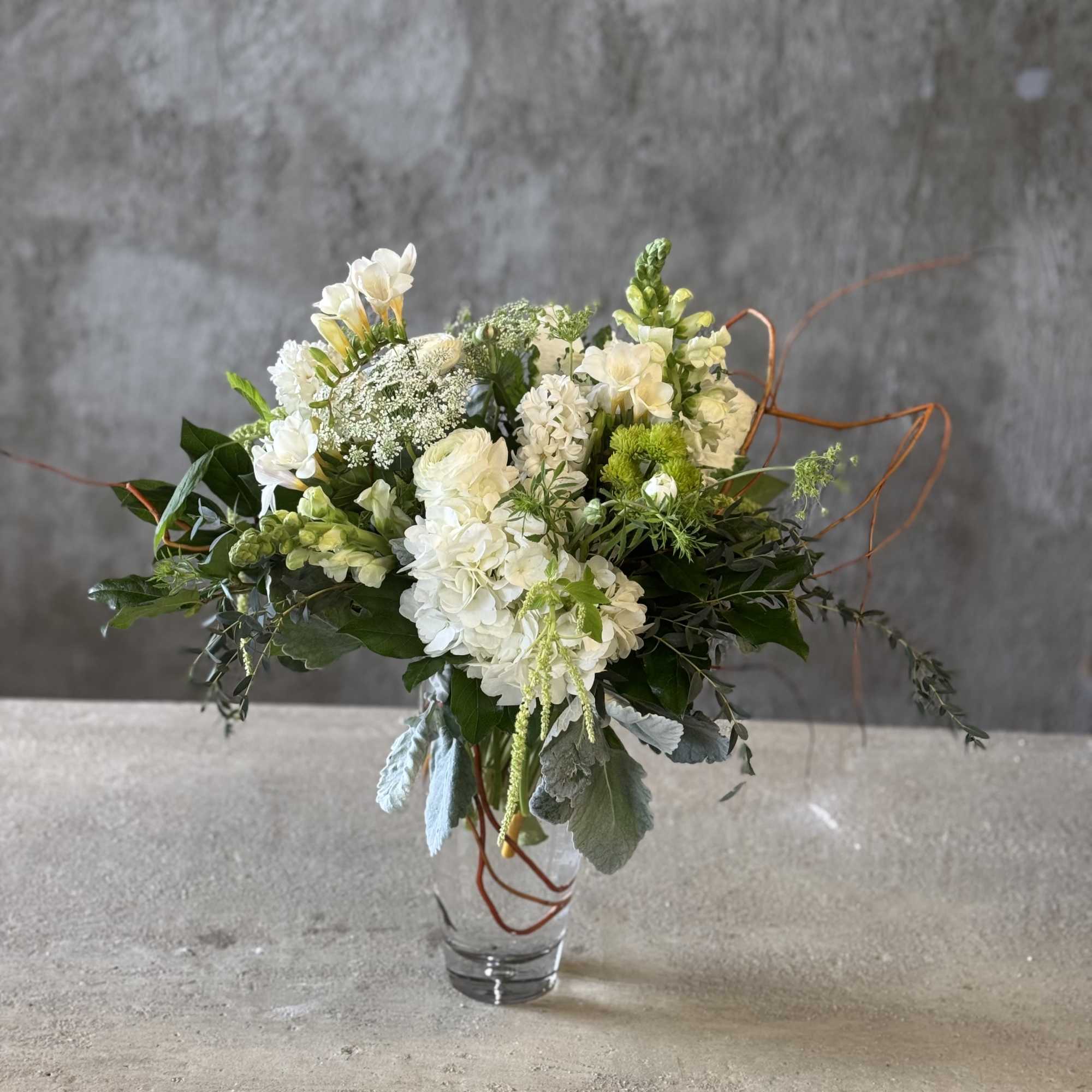 White and green floral arrangement in a clear glass vase