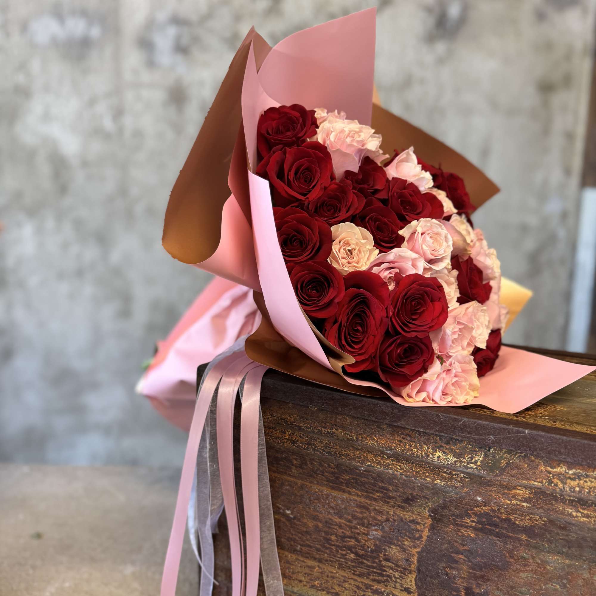 Bouquet of red and pale pink roses wrapped in pink paper