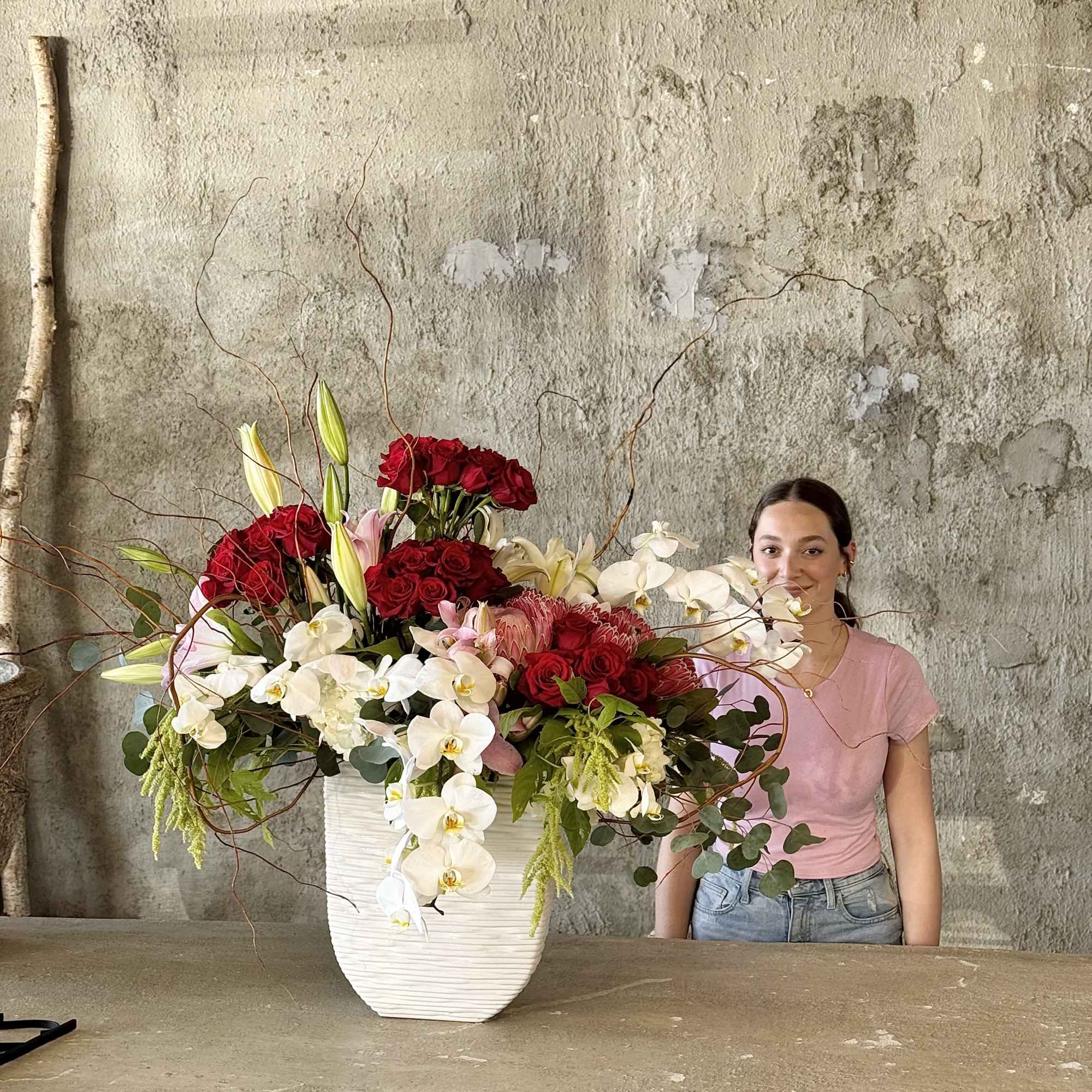 Large arrangement of red roses and white orchids in a white vase