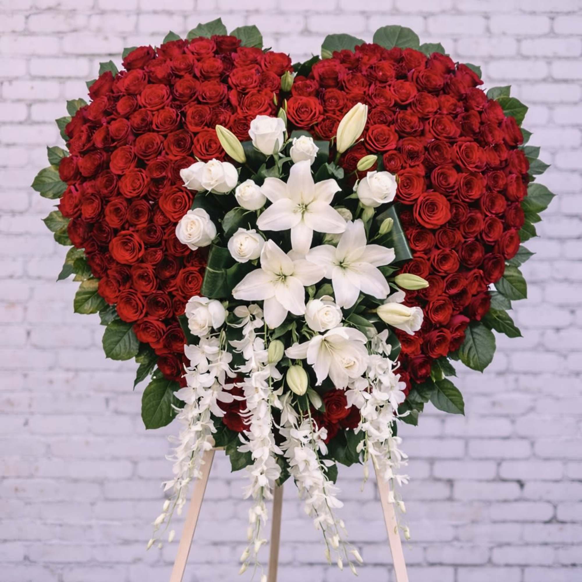 Heart-shaped red rose standing spray with white lilies and orchids