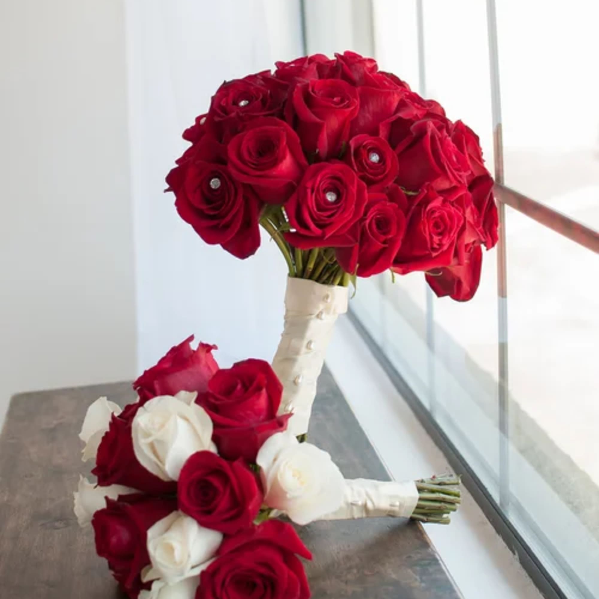 Two rose bouquets with red and white blooms, one tied with white ribbon