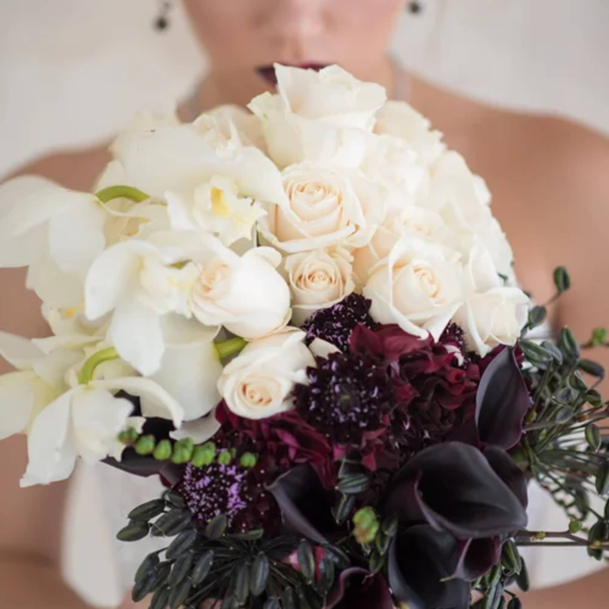 Bride holding a bouquet of white and dark burgundy flowers