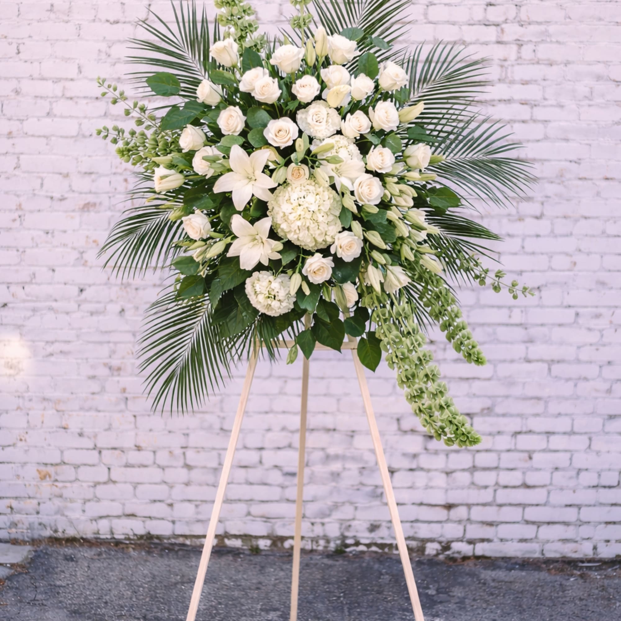 White floral standing spray on a wooden easel
