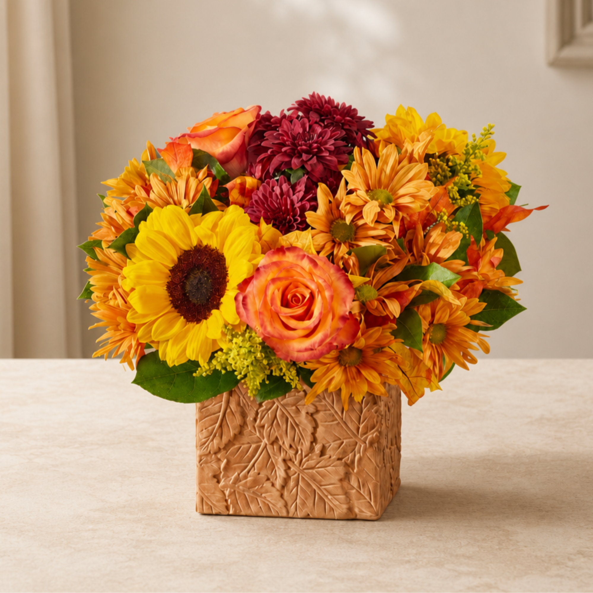 Mixed bouquet of sunflowers, roses, and mums in a carved square vase