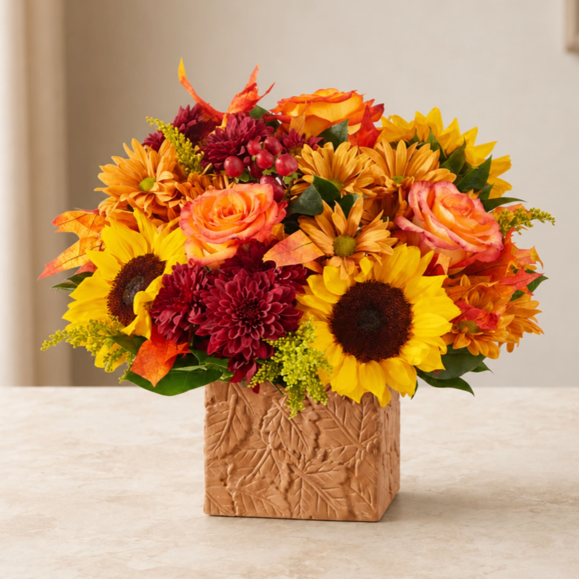 Autumn bouquet with sunflowers, roses, and mums in a textured square vase