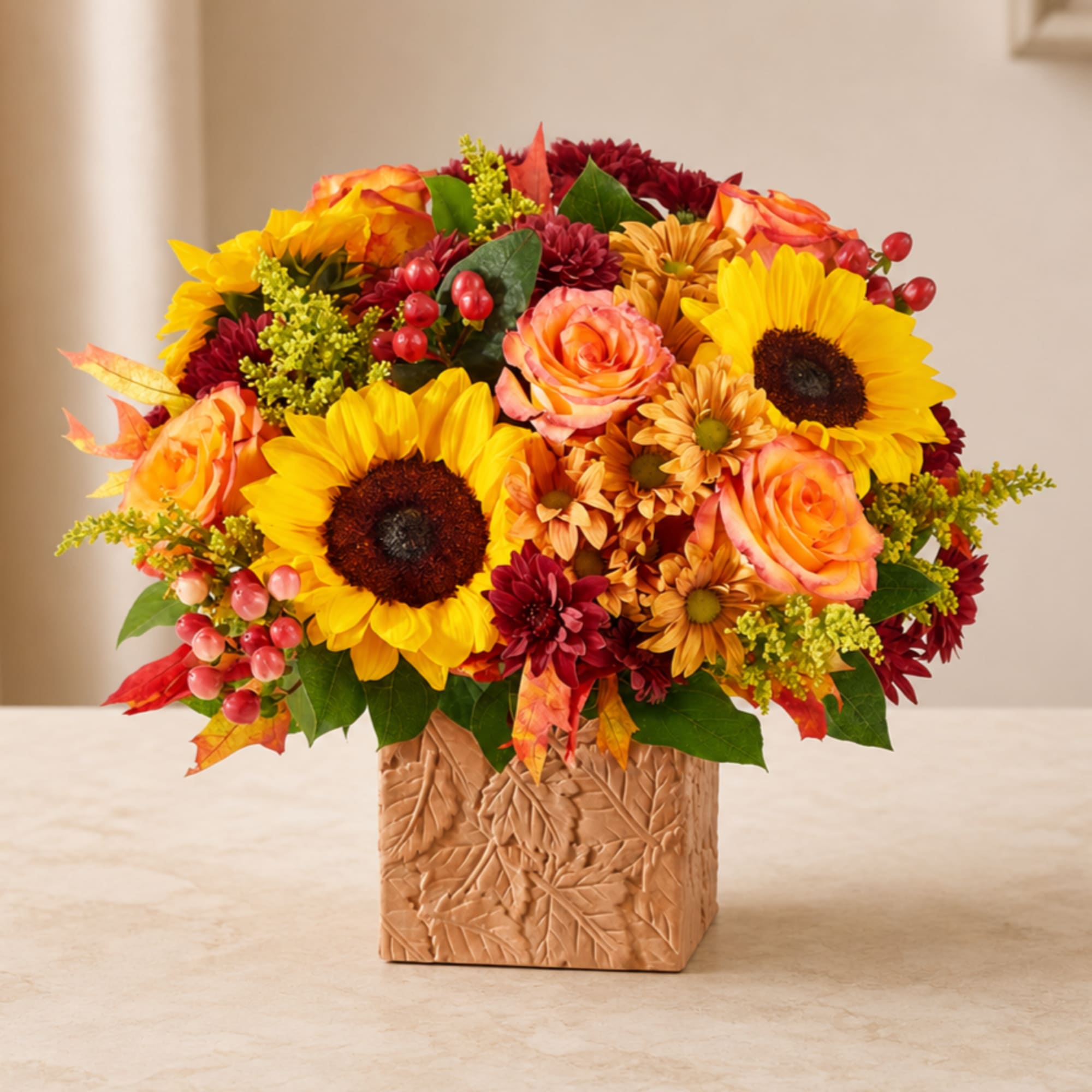 Sunflower and rose arrangement in a leaf-patterned square vase