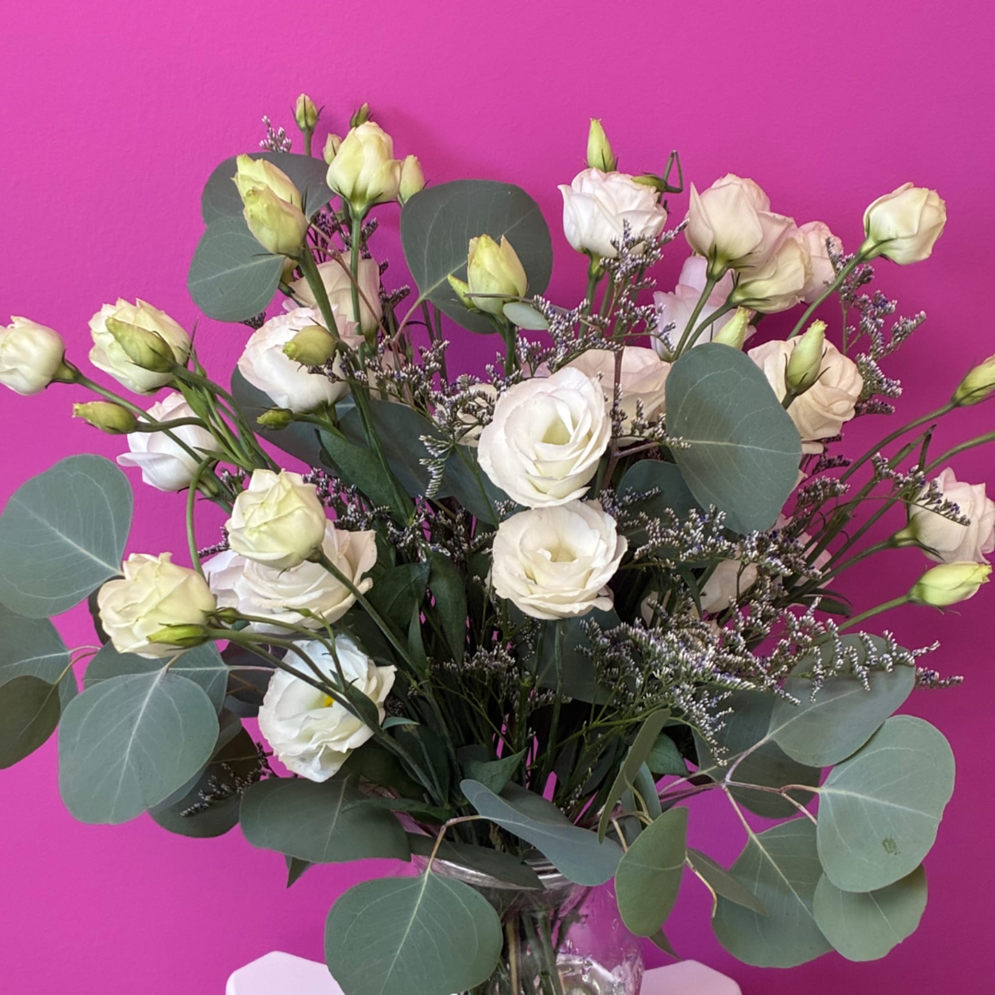 White lisianthus bouquet in a glass vase with round eucalyptus leaves