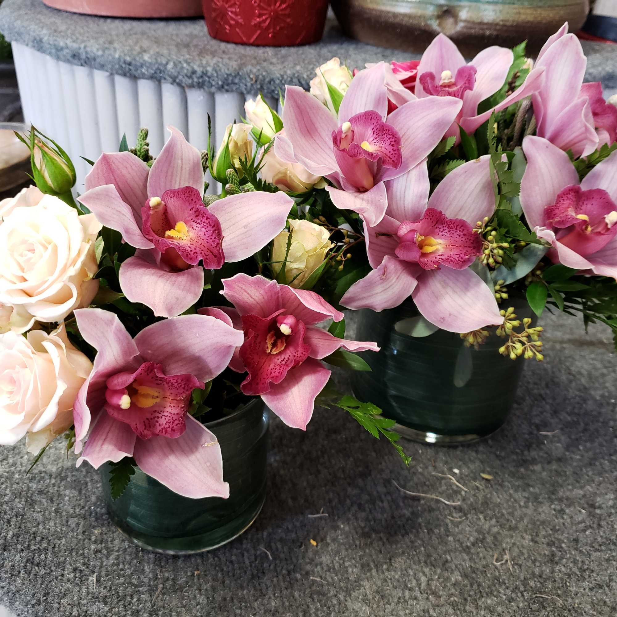 Elegant cymbidum orchids are showcased in a cylinder vase, accompanied by spray