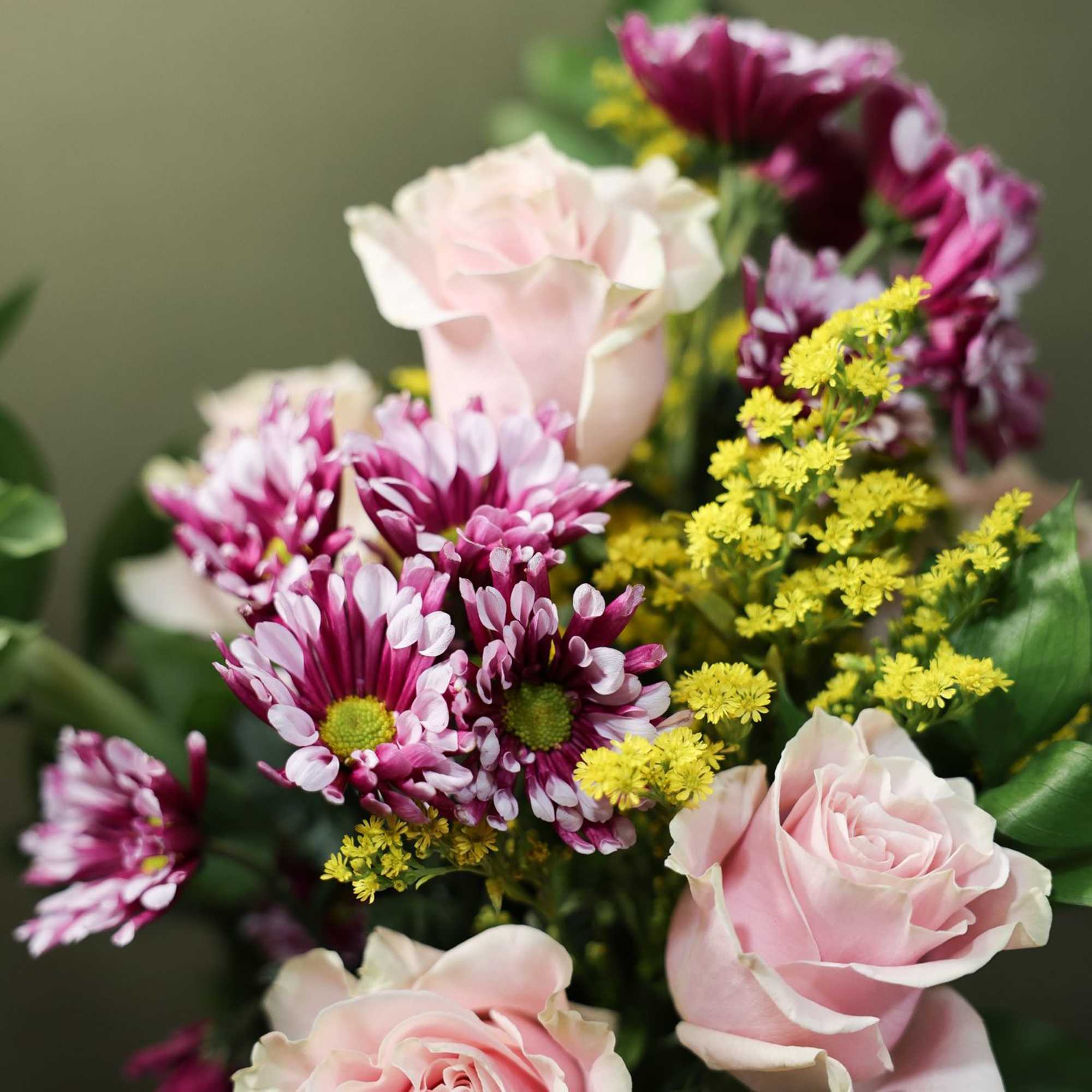 Bouquet of pale pink roses and purple daisies with yellow filler flowers