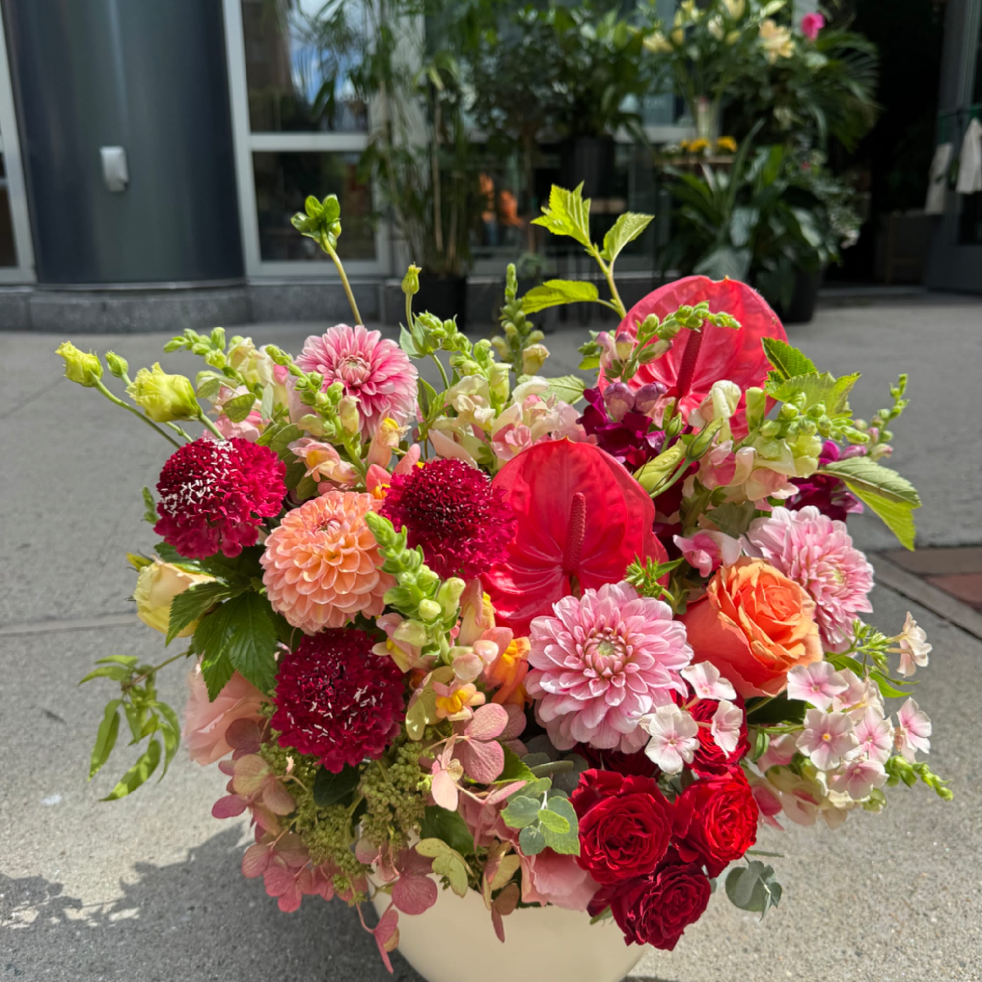 Colorful mixed bouquet in a white vase with pink, red, orange, and peach blooms