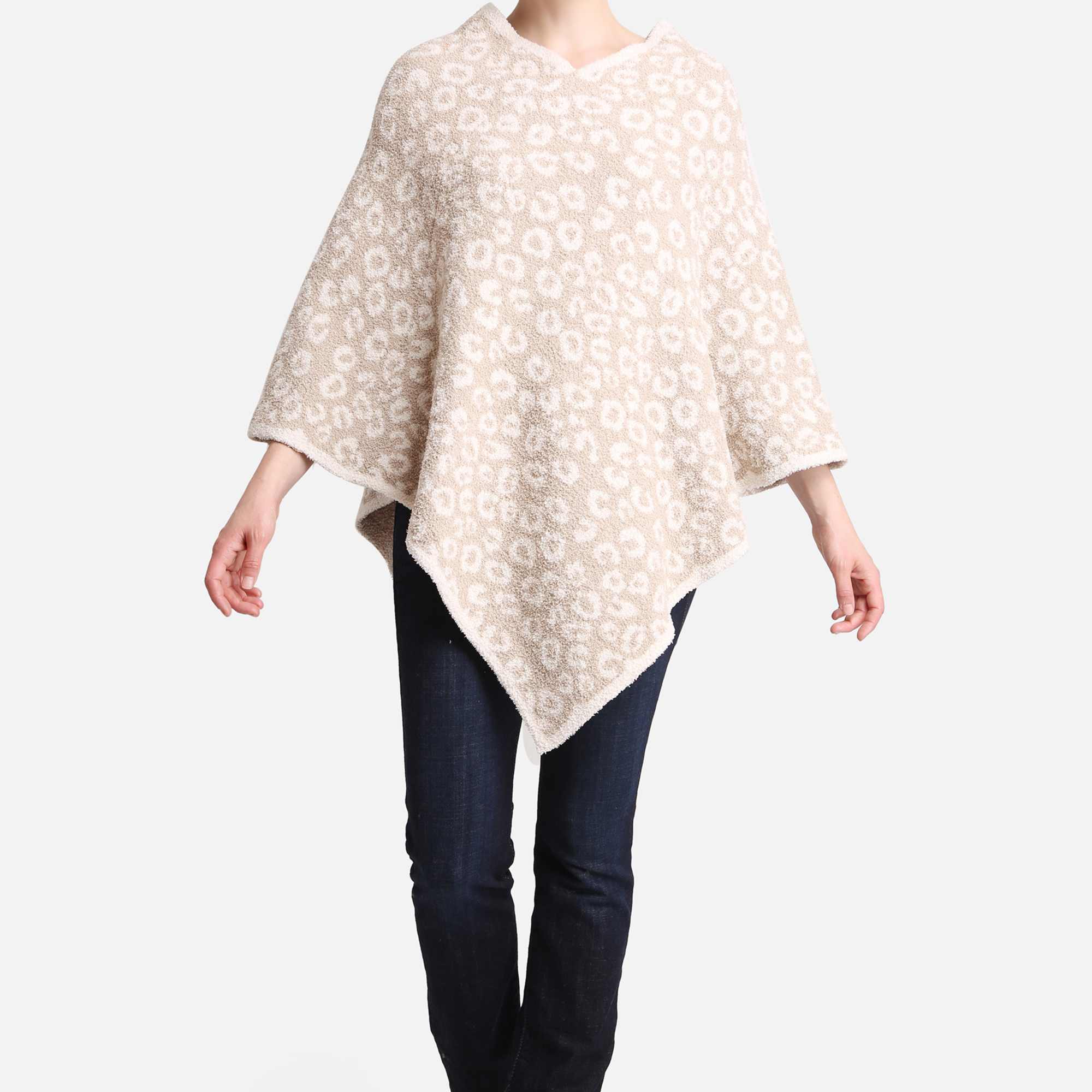 Woman wearing a soft beige and white patterned poncho with dark jeans and black boots