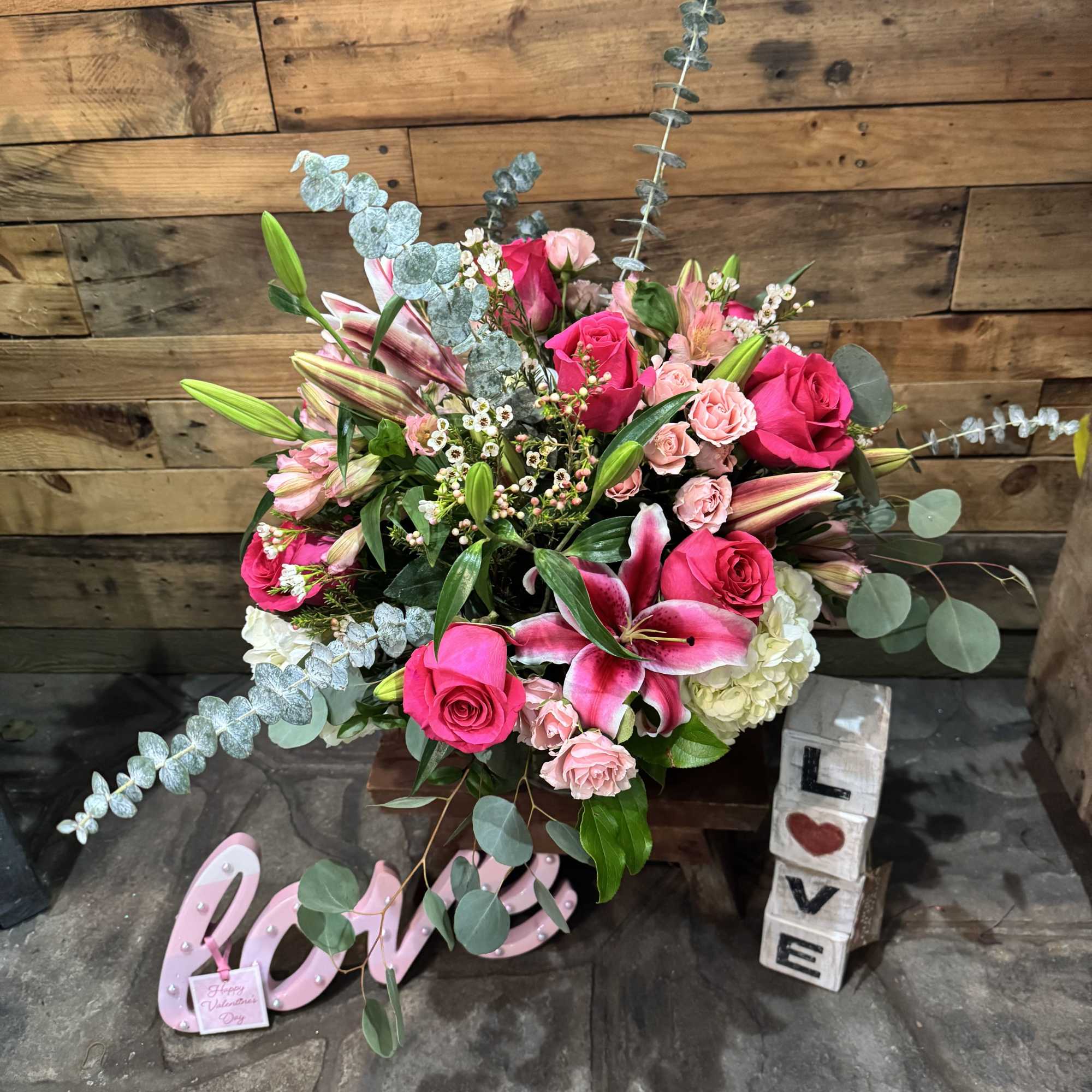 Pink roses and lilies arranged with eucalyptus in a decorative display