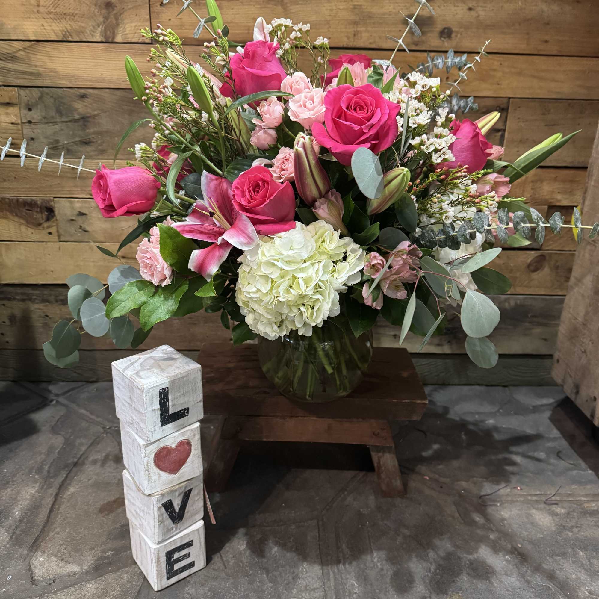 Pink rose bouquet in a glass vase with a LOVE block decoration