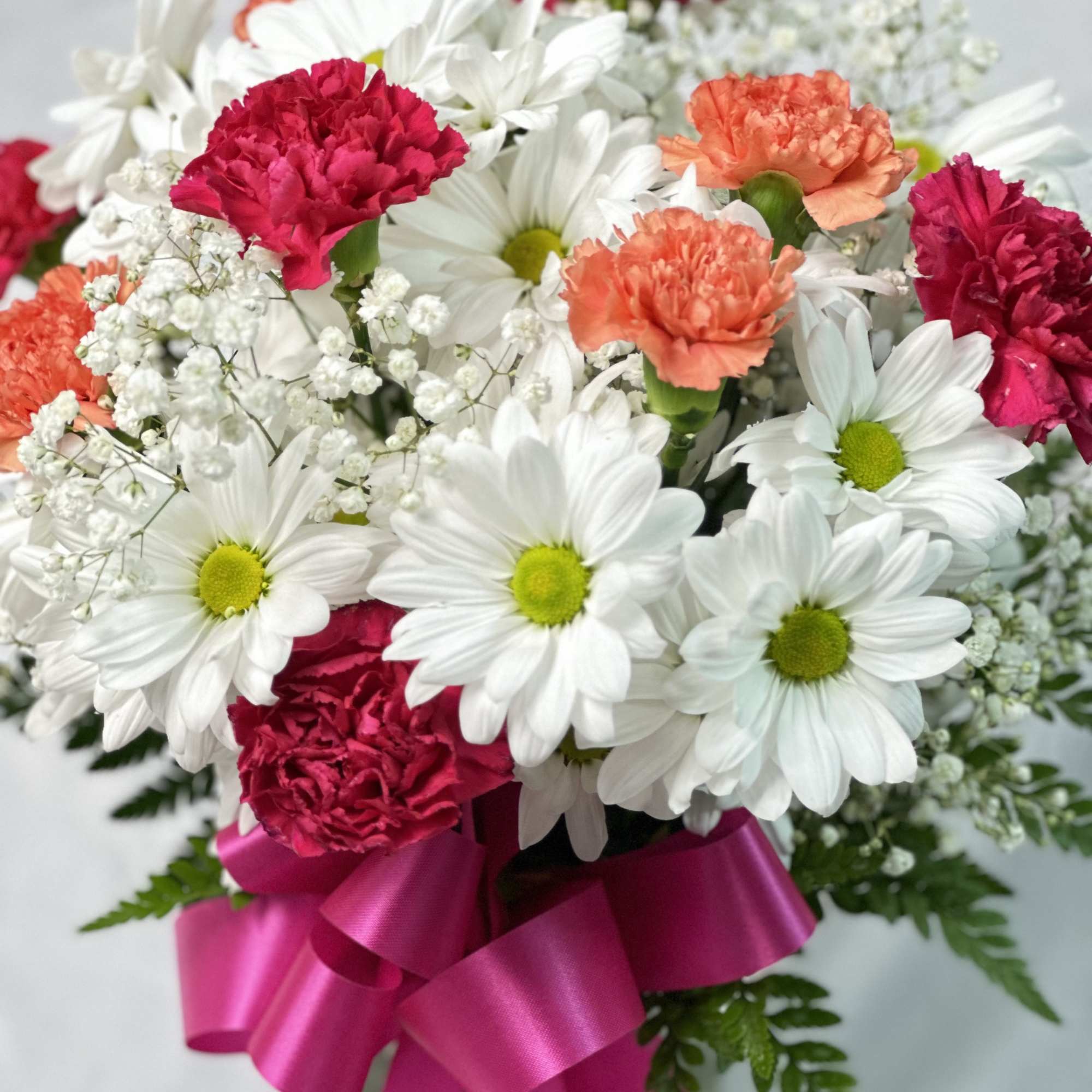 Bouquet of white daisies and pink carnations with a magenta ribbon