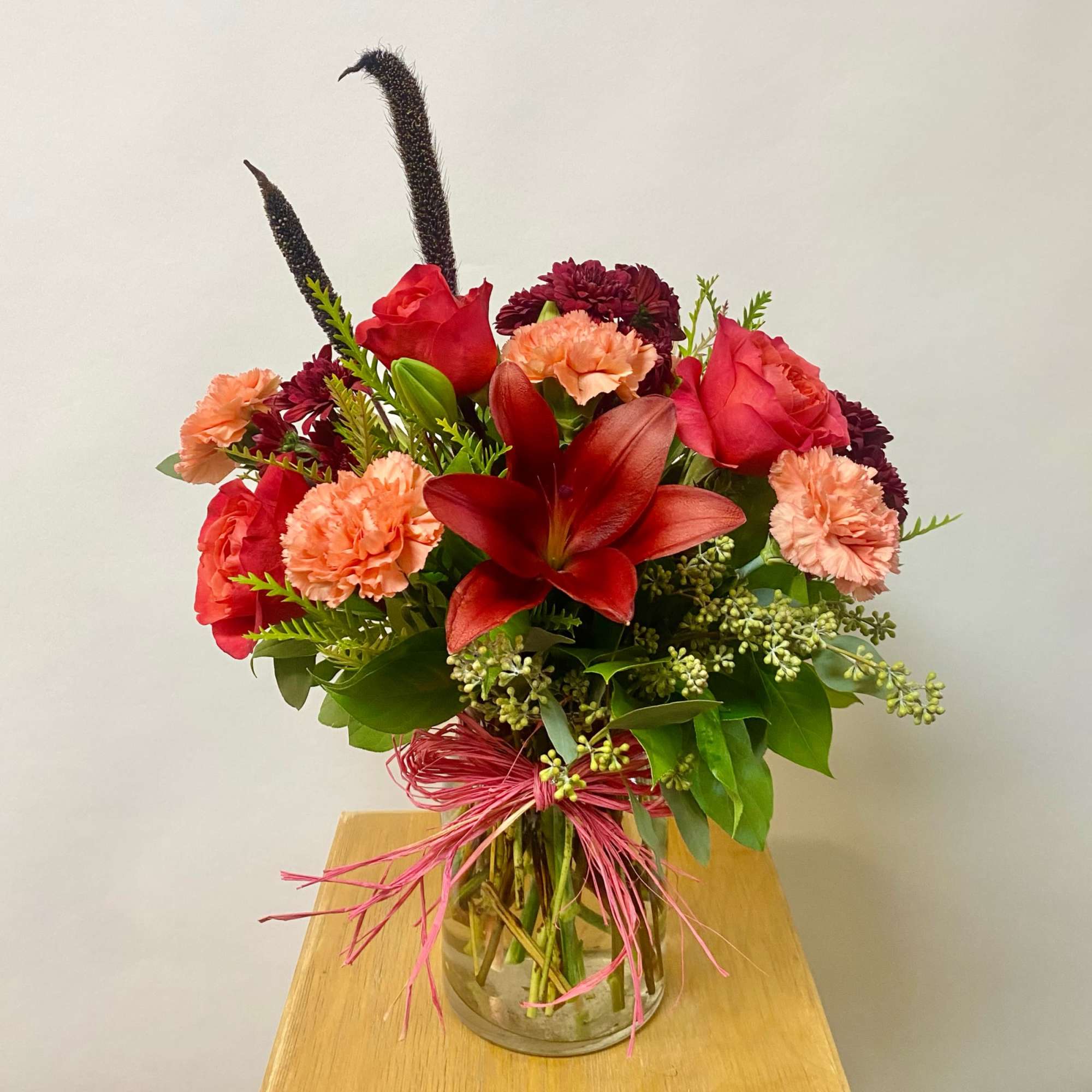 Bouquet of red lilies, roses, and carnations in a glass vase