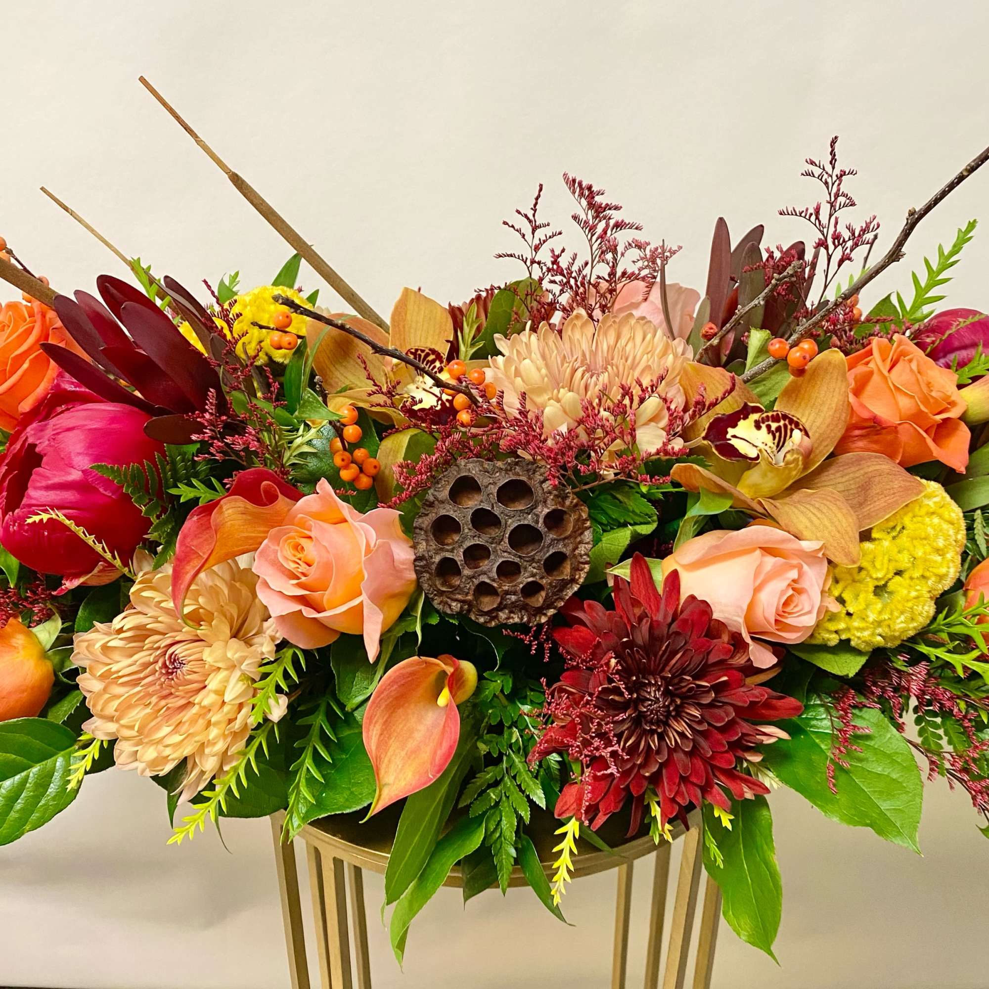 Mixed floral arrangement in a gold vase with roses, chrysanthemums, and calla lilies