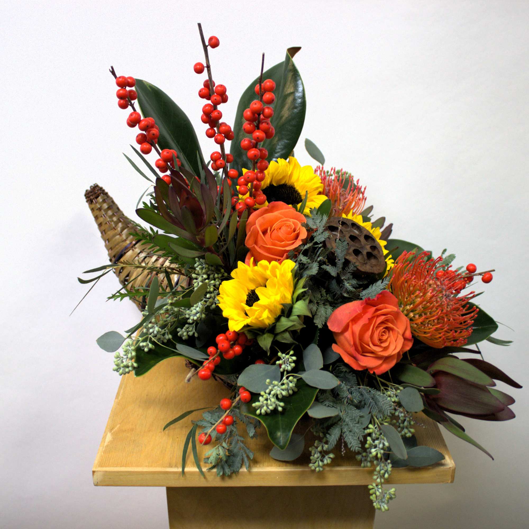 Mixed floral arrangement with sunflowers, orange roses, and red berry stems