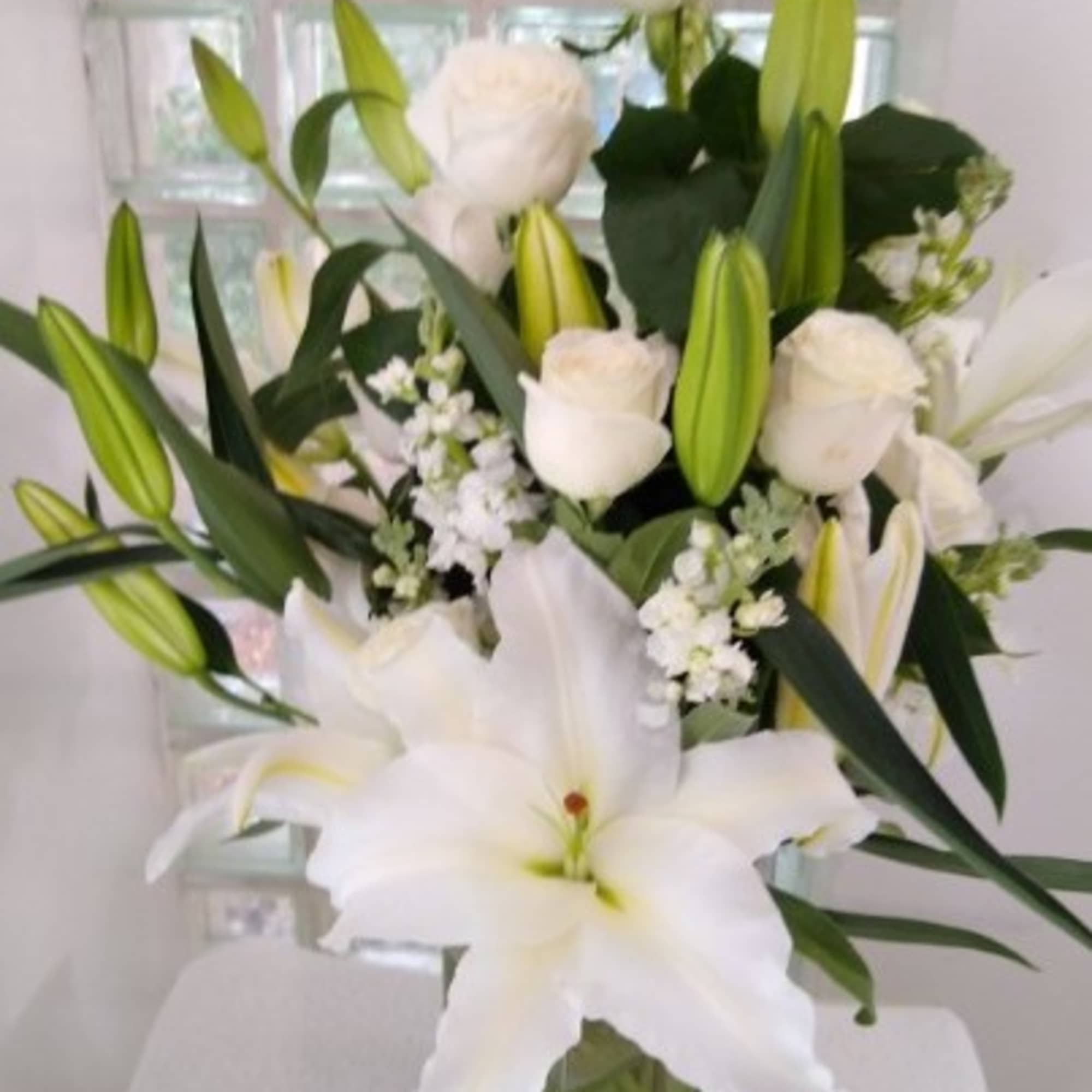 White lilies and roses arranged in a clear glass vase