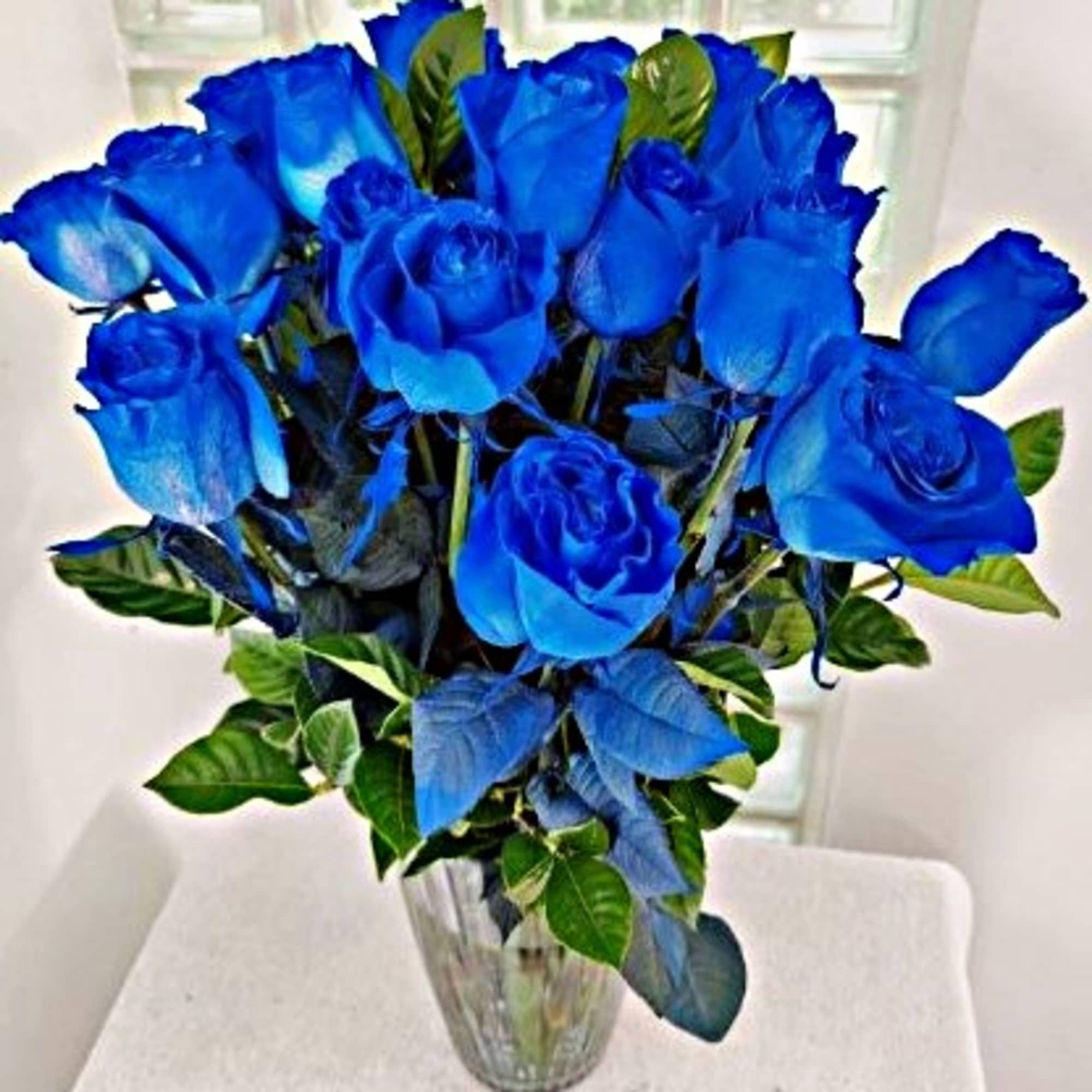 Blue roses arranged in a clear glass vase