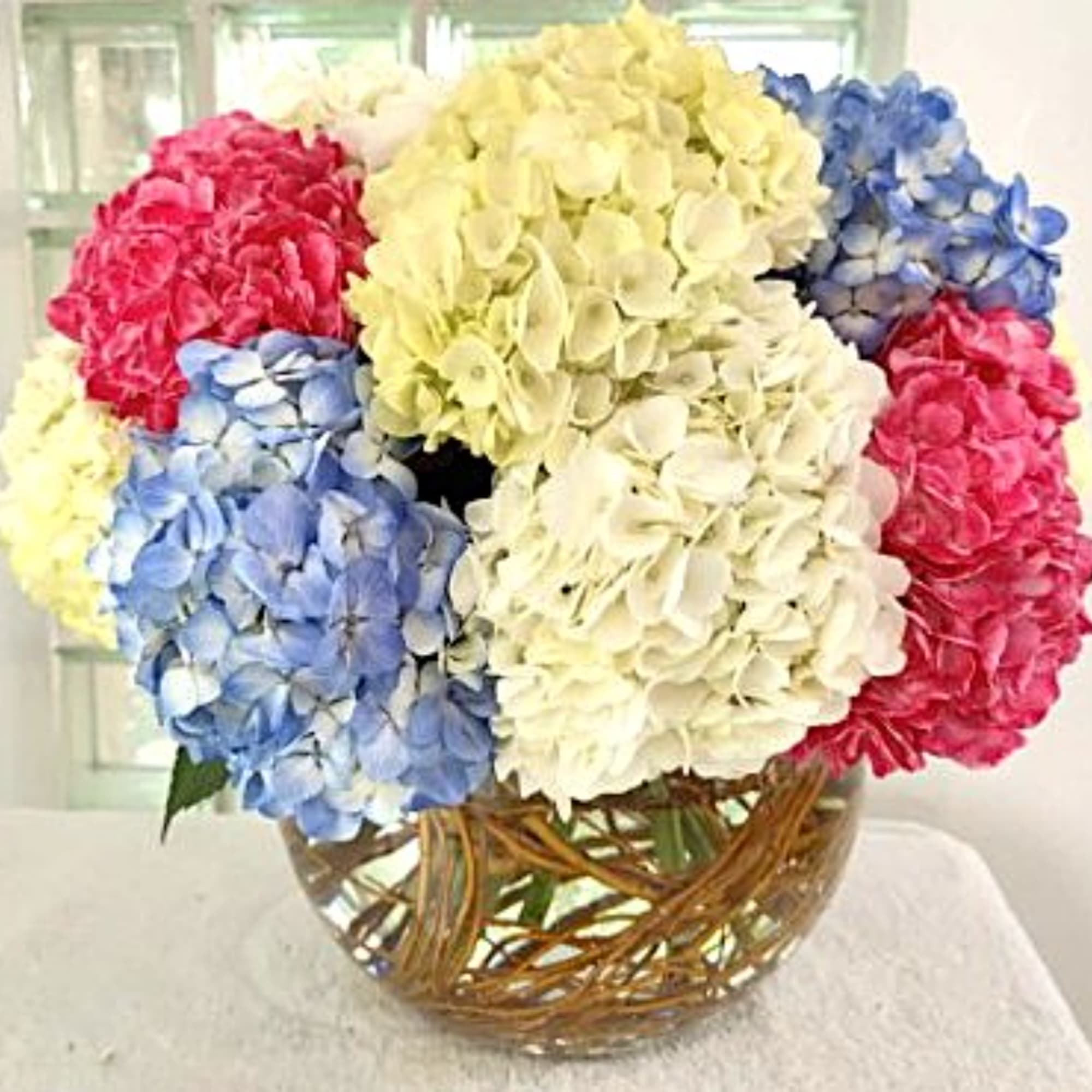 Colorful hydrangea bouquet in a round glass vase