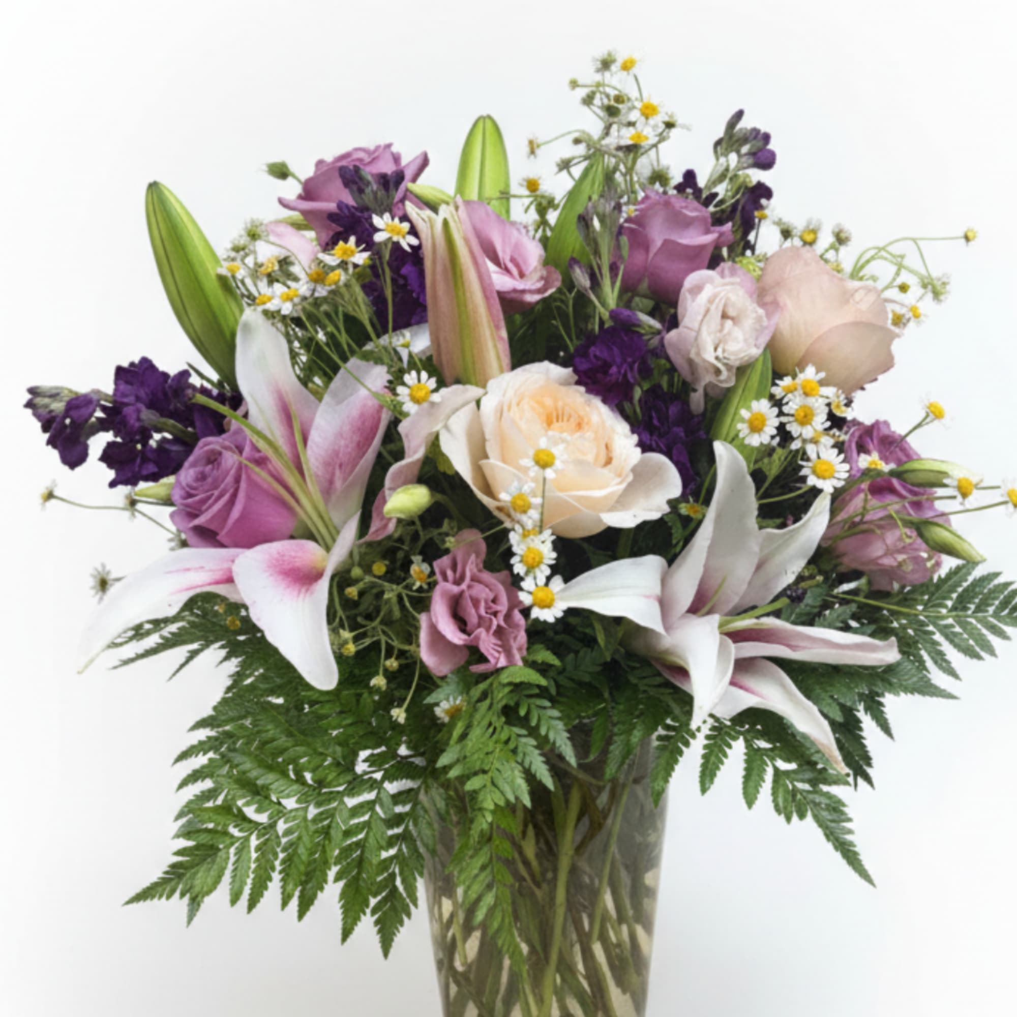 Mixed bouquet of lilies, roses, and purple flowers in a glass vase