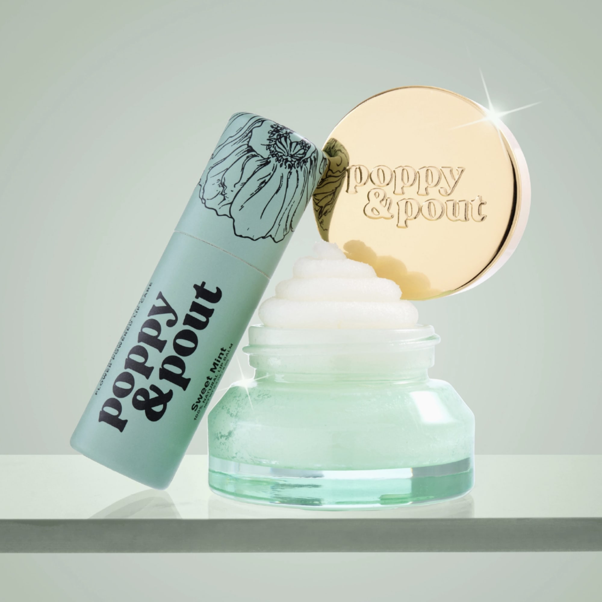 Mint lip balm tube beside an open jar of cream with a gold lid