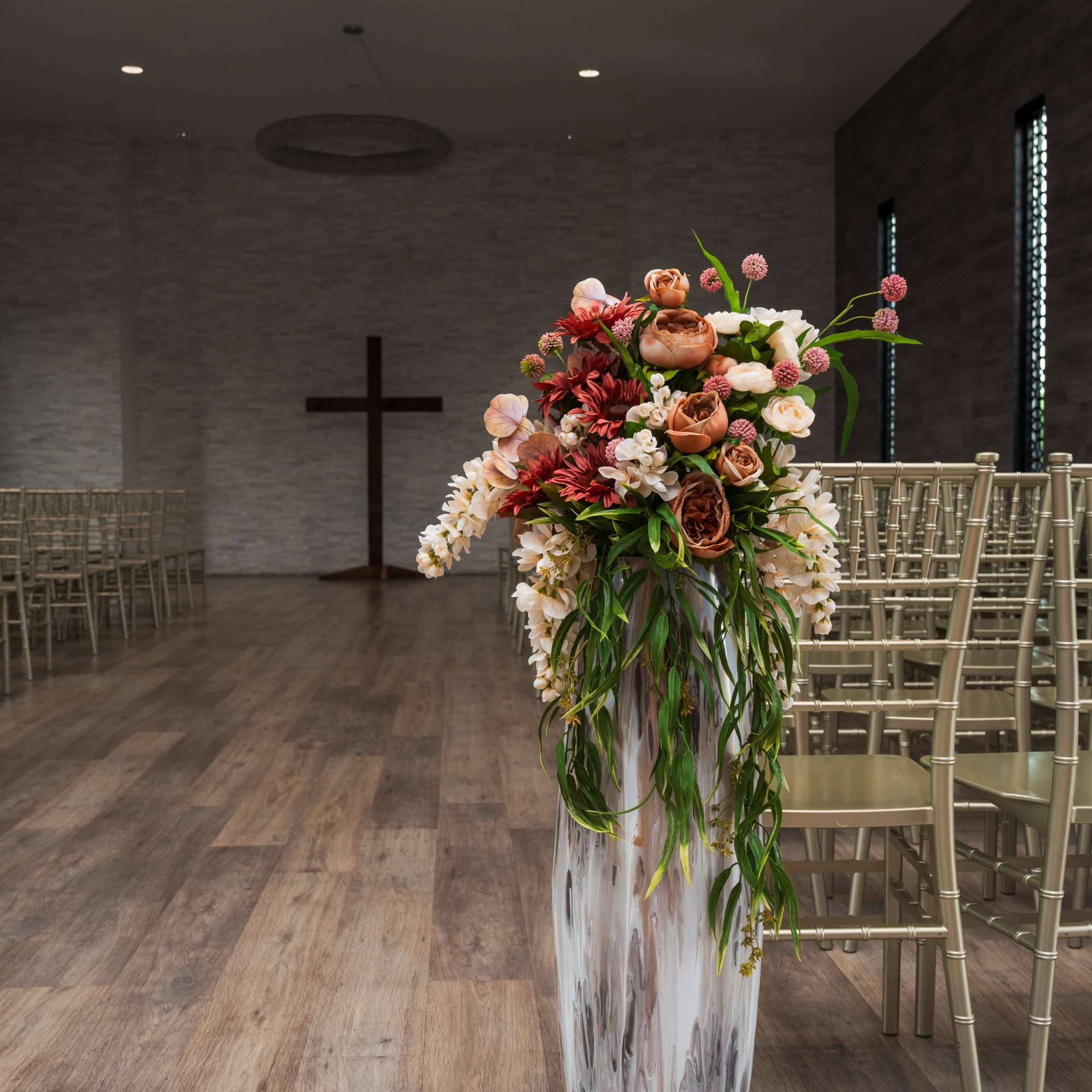 Tall floral arrangement in a silver vase inside a ceremony space