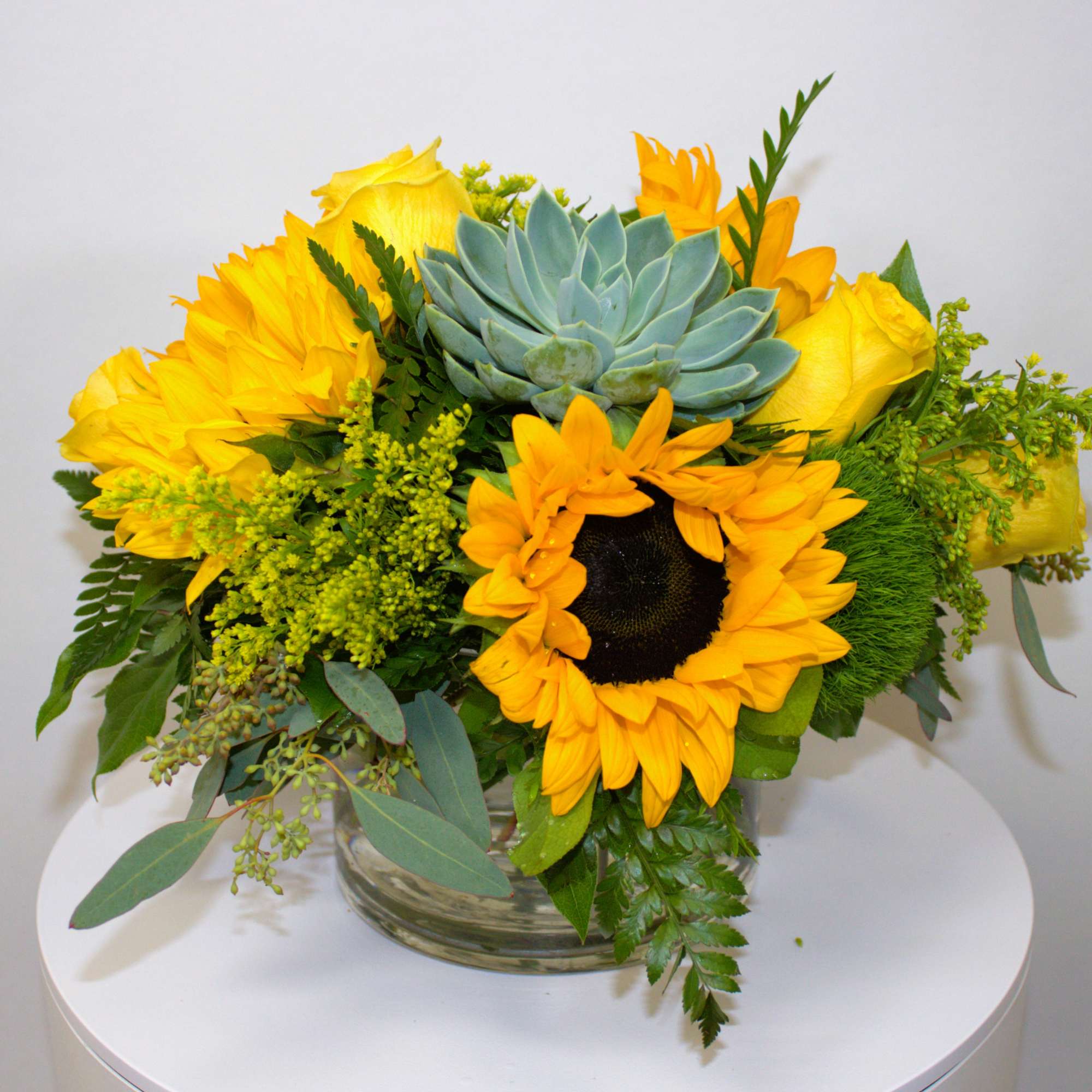 Yellow sunflower and succulent arrangement in a glass vase