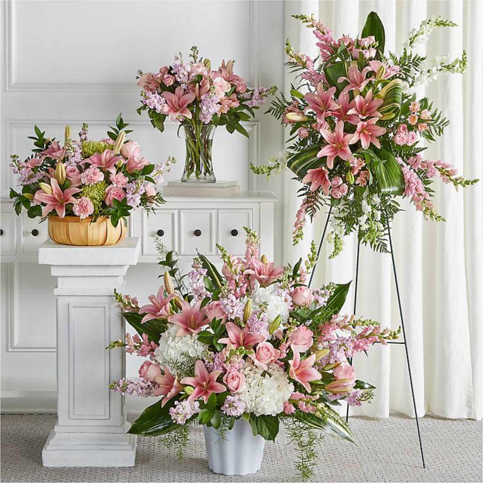 Pink lily and rose arrangements in vases and a basket