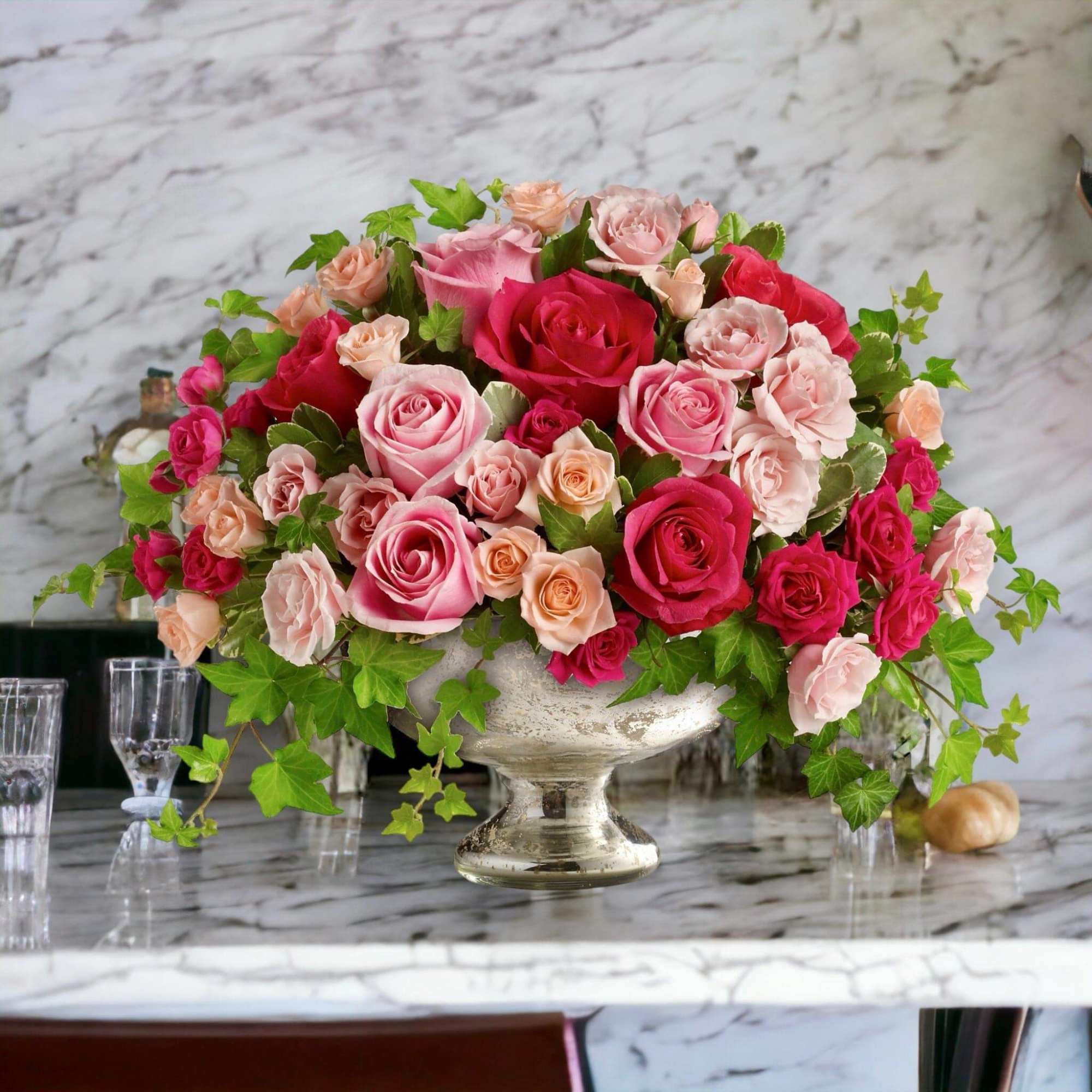 Pink and red roses arranged in a silver pedestal vase