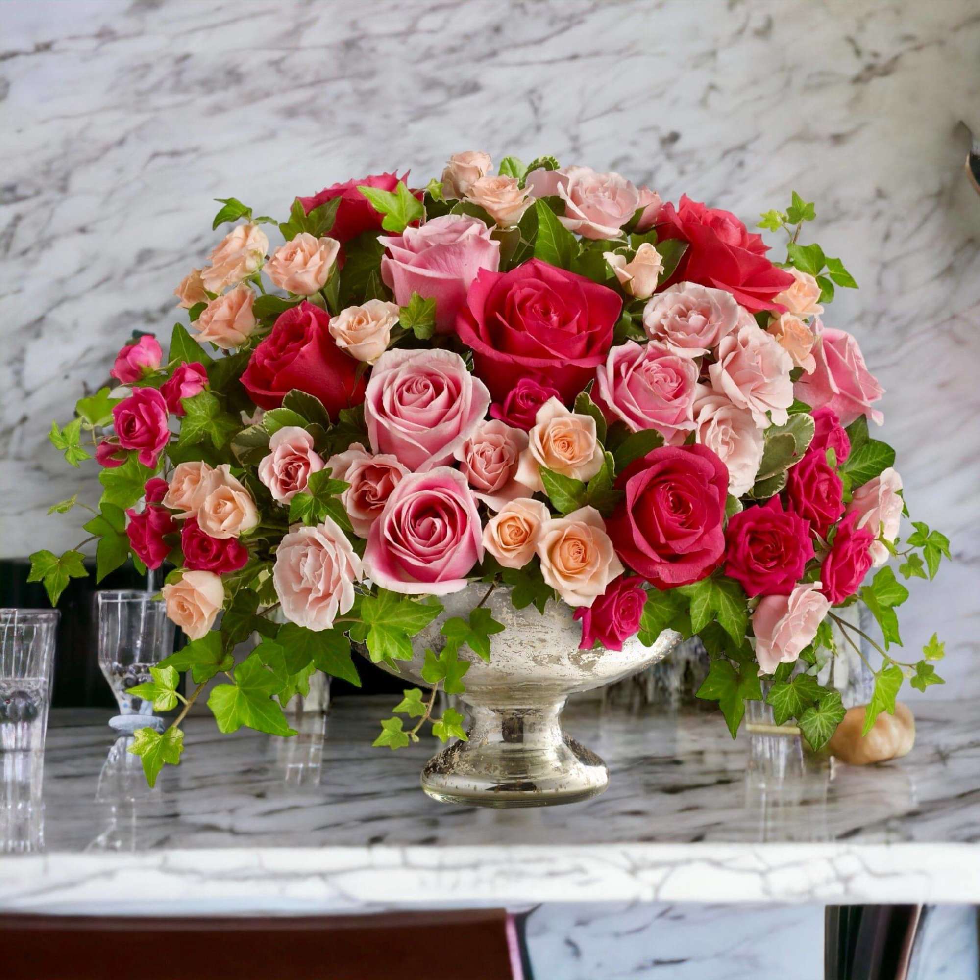 Pink and red roses arranged in a silver pedestal bowl