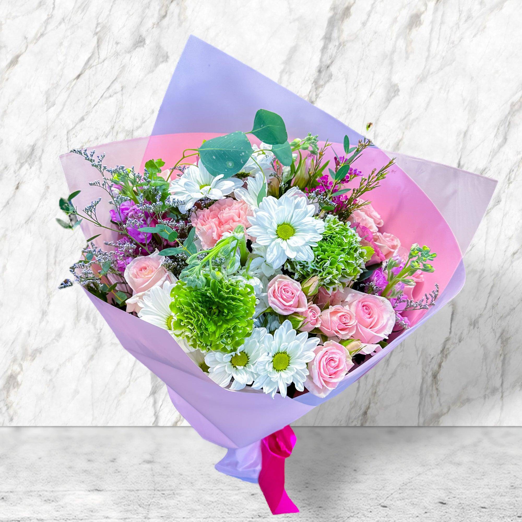 Bouquet of pink roses, white daisies, and green carnations wrapped in purple paper
