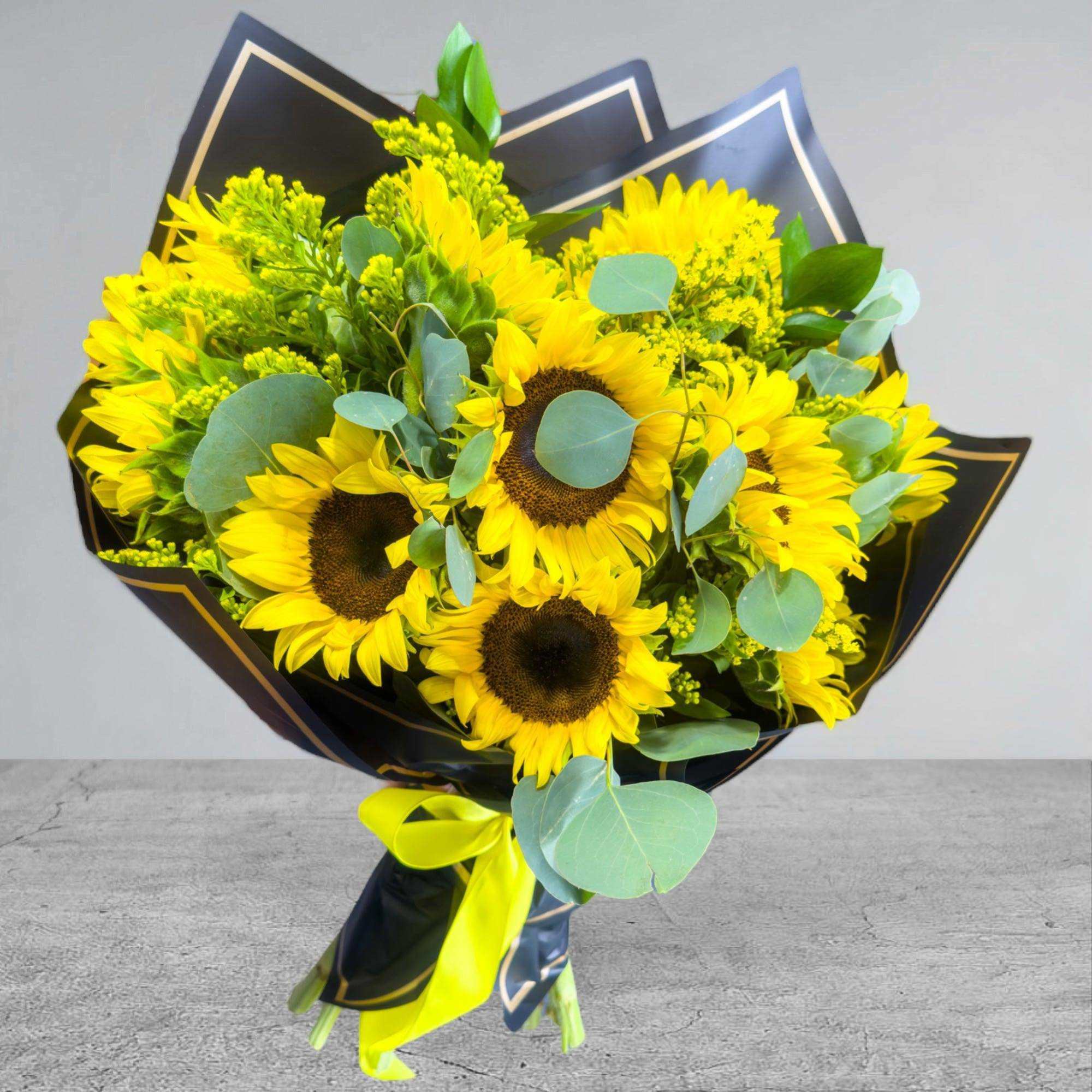 Bouquet of yellow sunflowers wrapped in black paper with a yellow ribbon