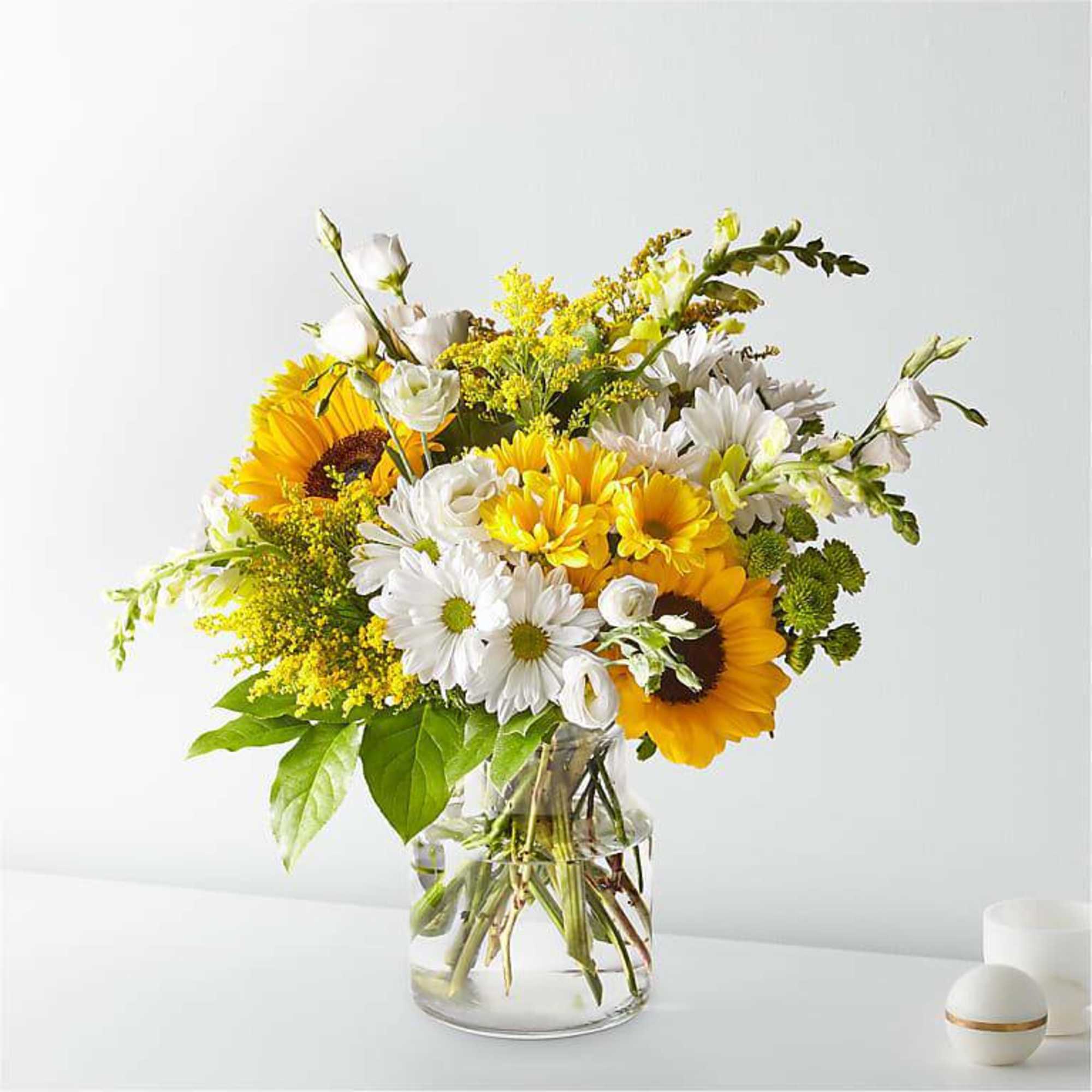 Bouquet of sunflowers and white daisies in a clear glass vase