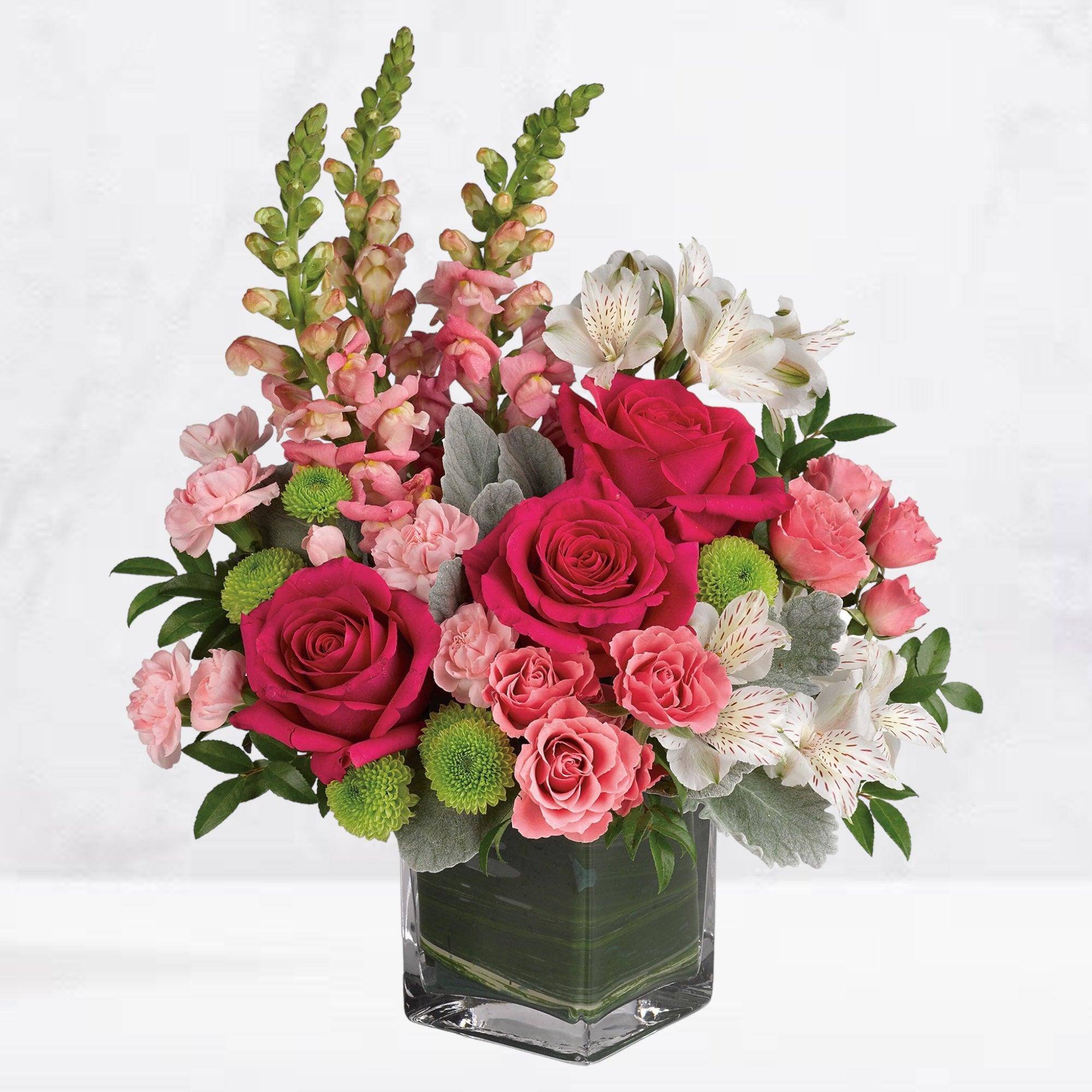 Pink roses and white alstroemeria in a clear square vase