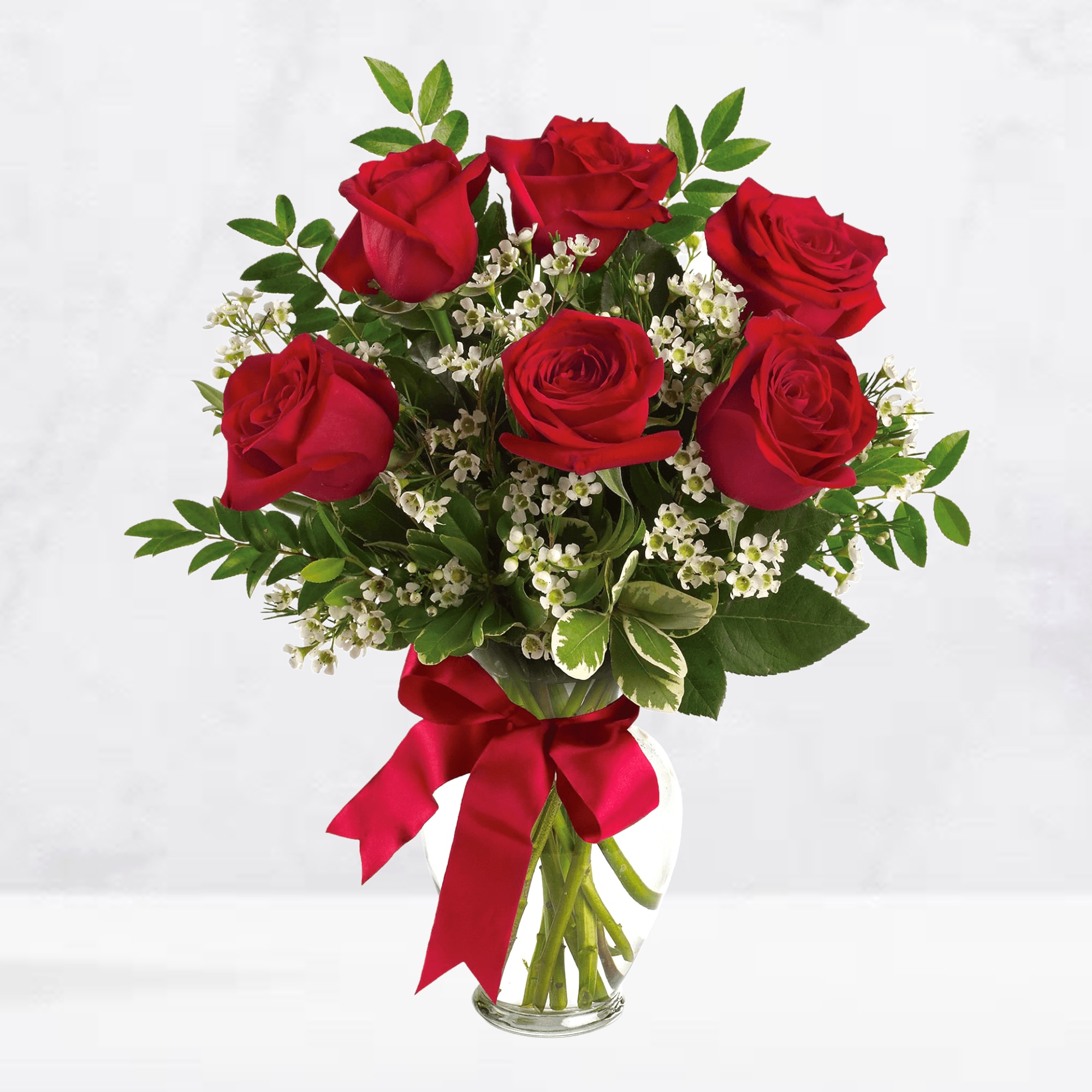 Red roses in a clear glass vase with a red ribbon