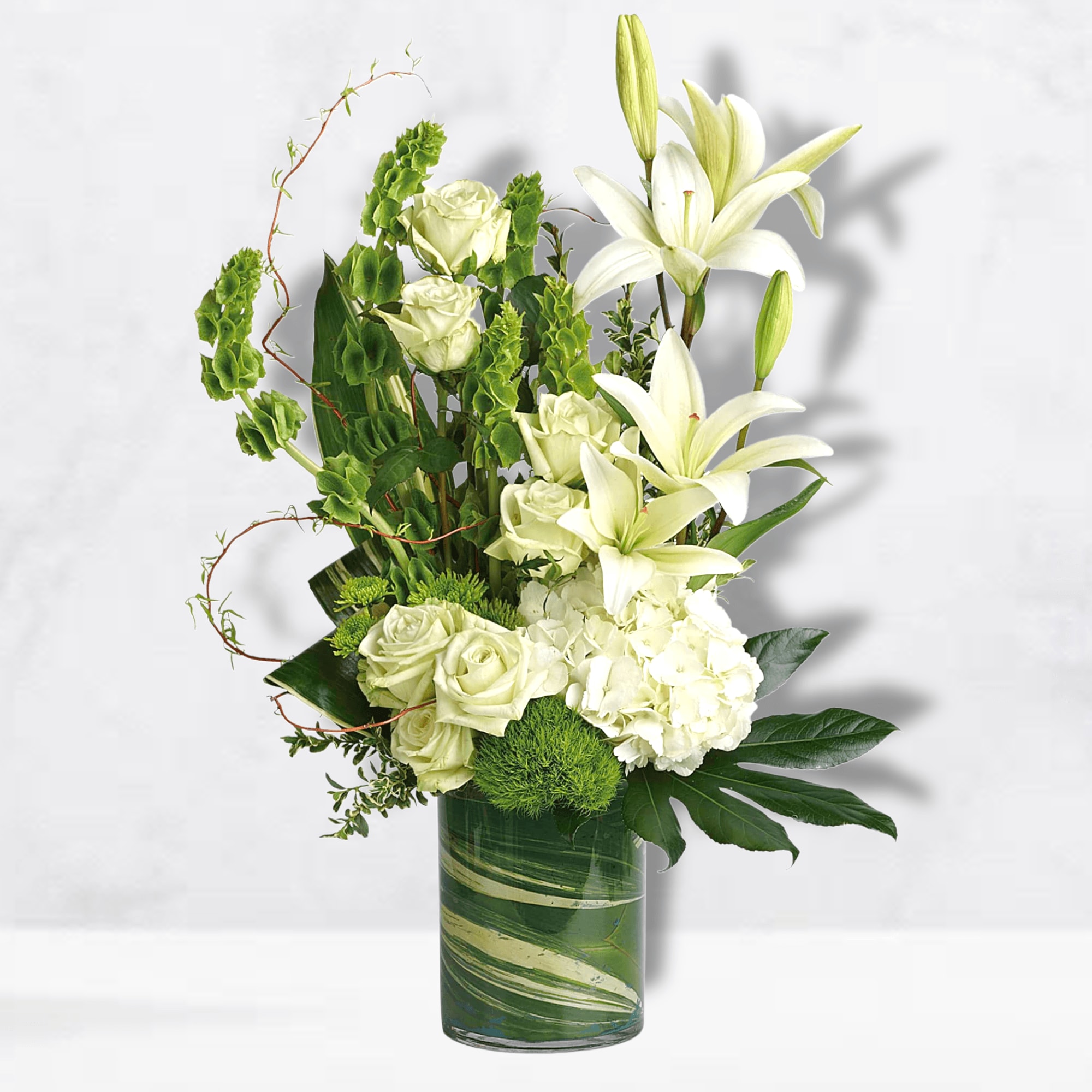White lilies and roses arranged in a green glass vase