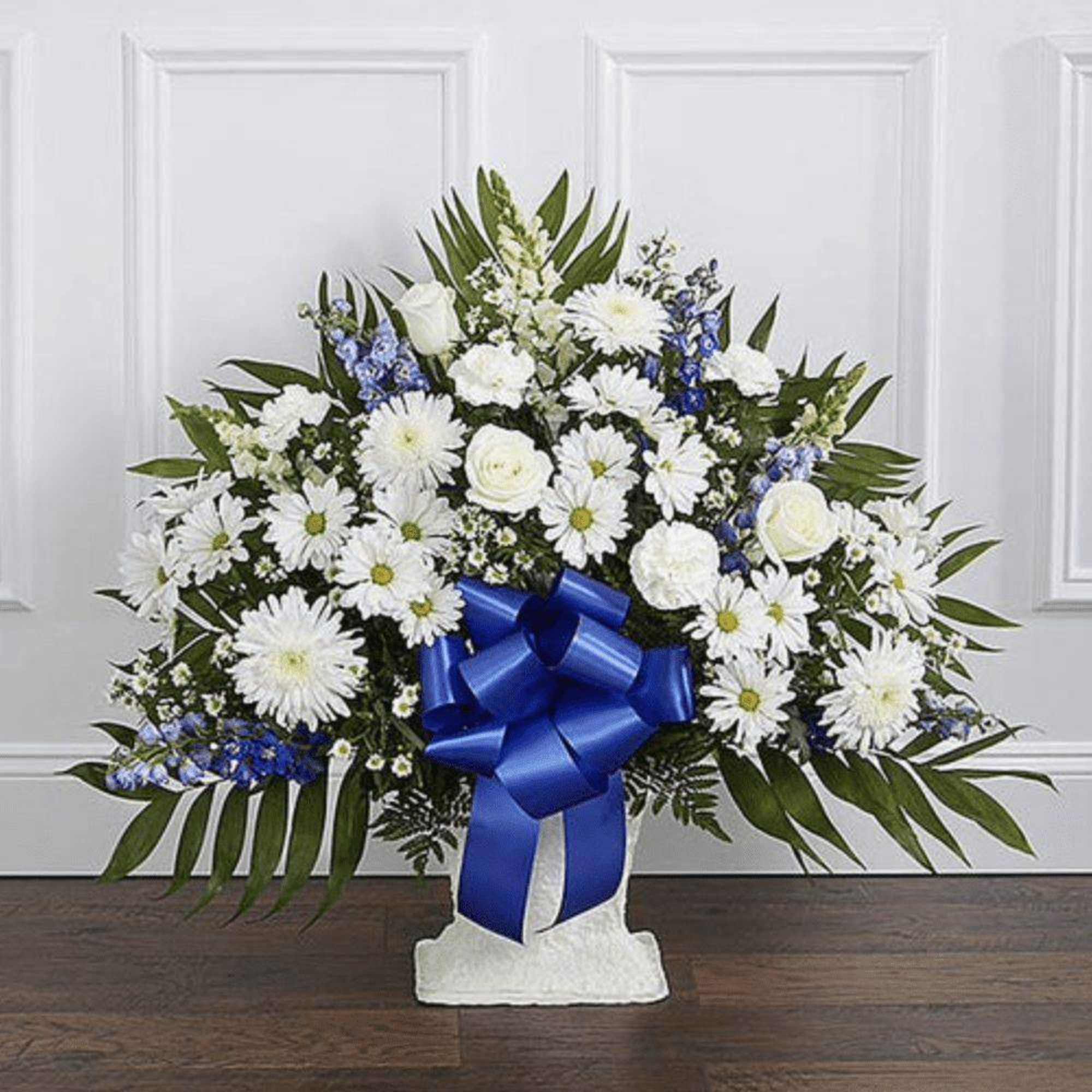 White floral standing spray with a blue ribbon on a pedestal base