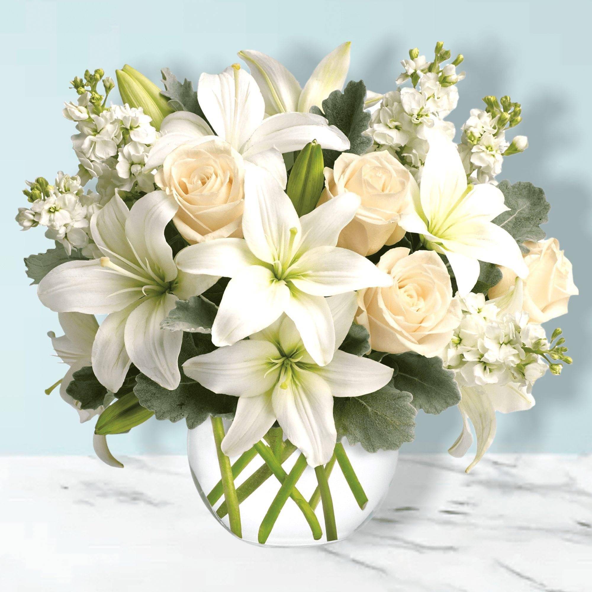 White lilies and cream roses in a clear glass vase