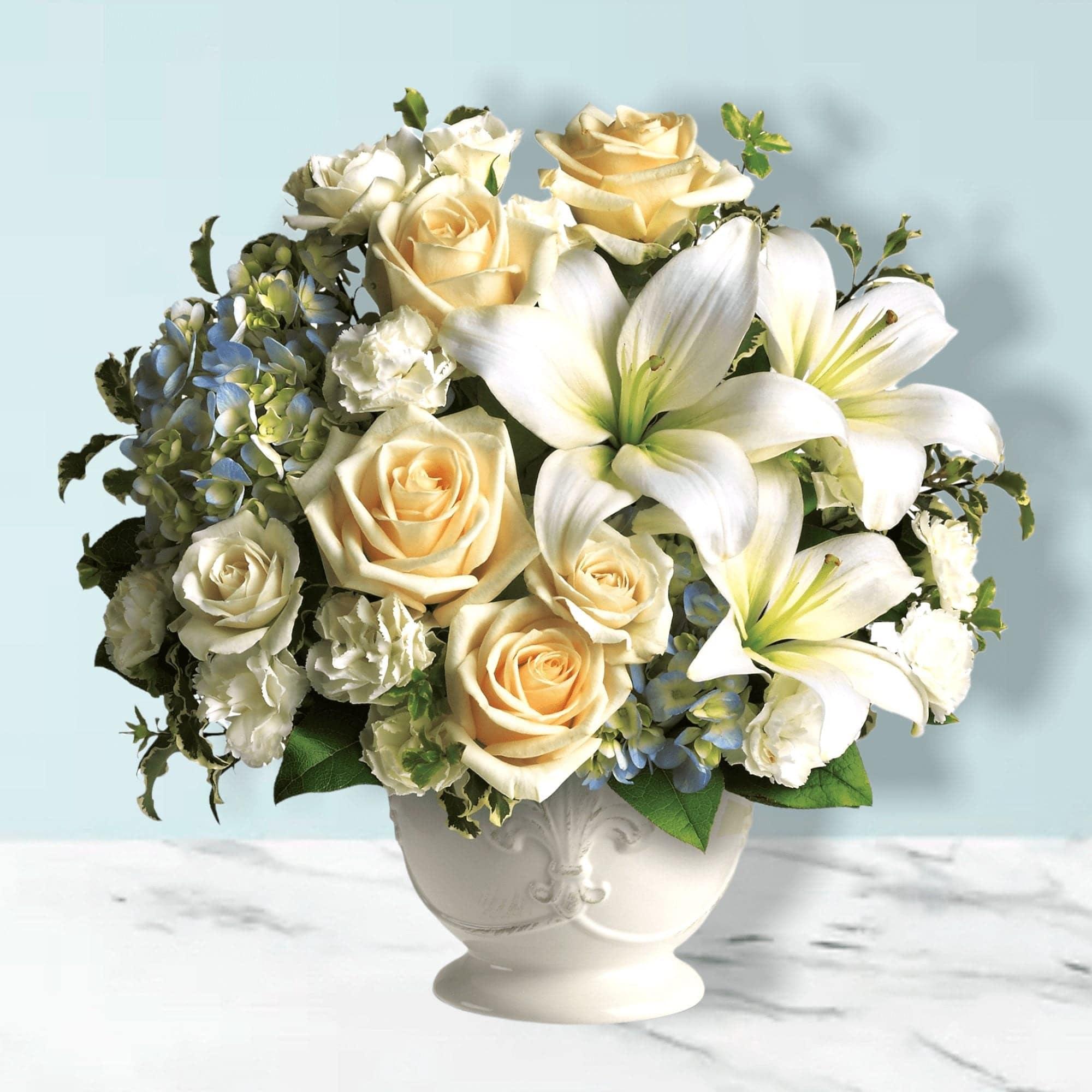 Cream roses and white lilies in a white vase