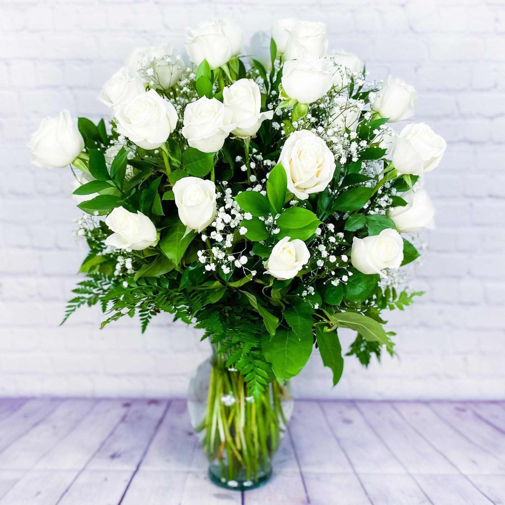 White rose bouquet in a clear glass vase with baby's breath