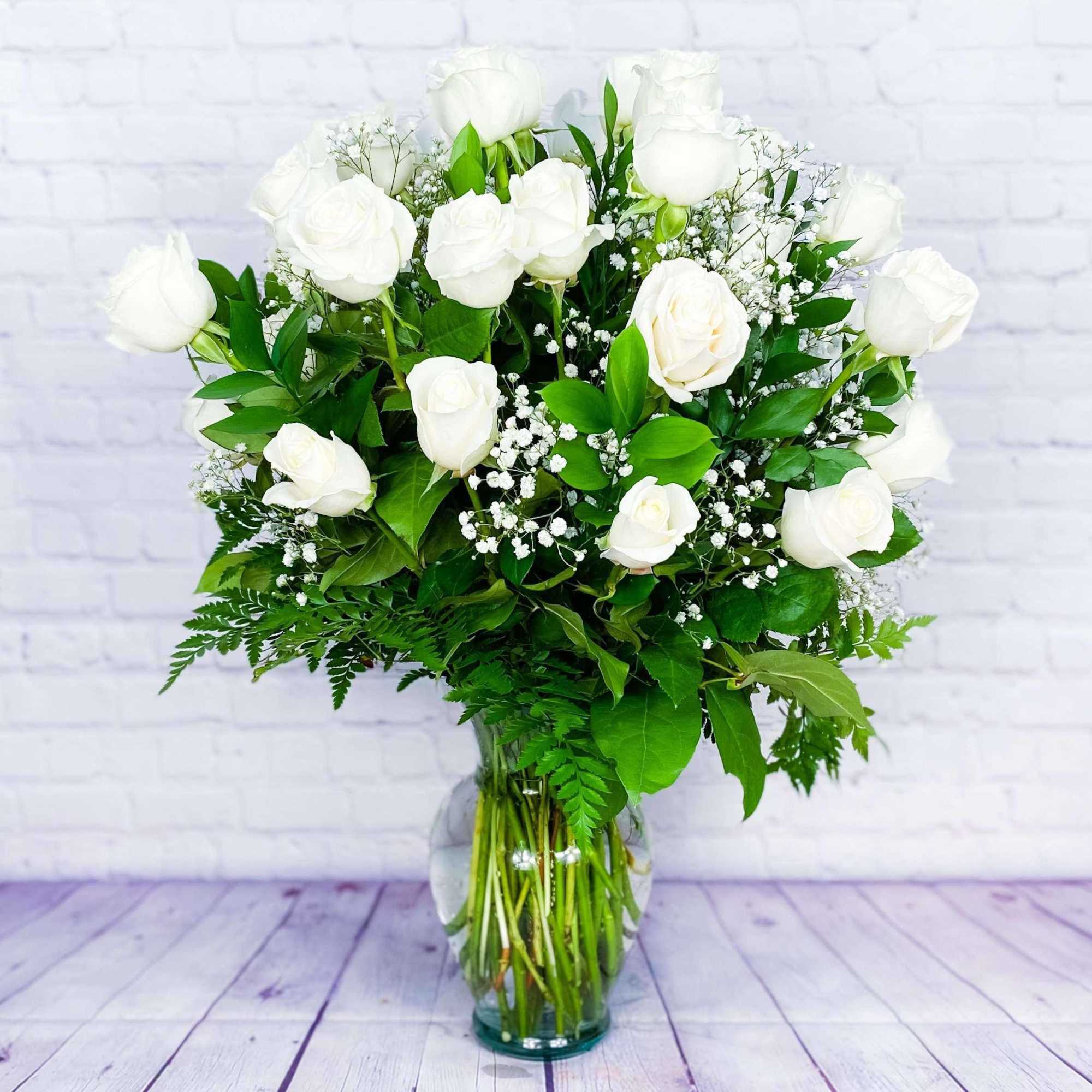 White roses arranged in a clear glass vase with baby's breath