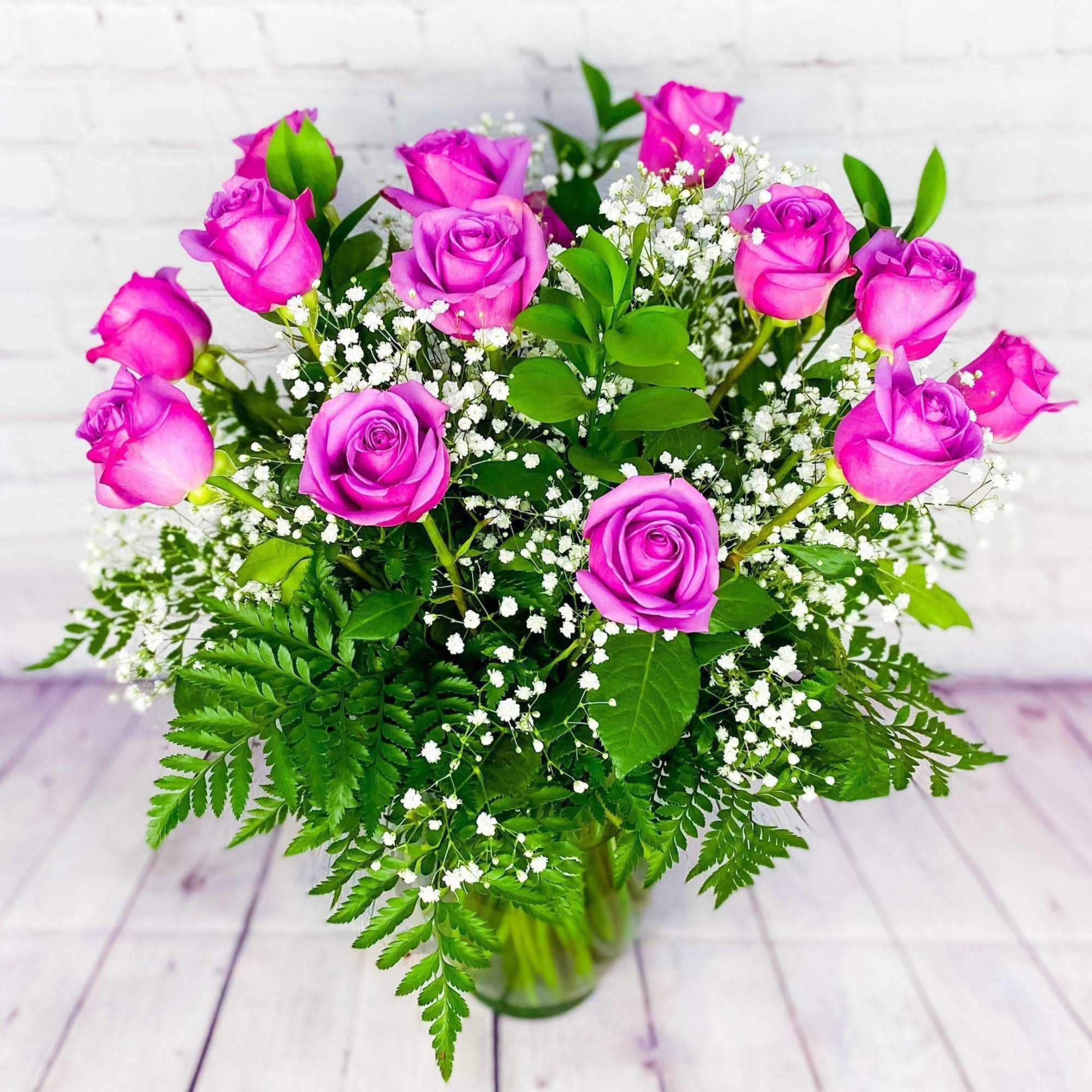 Pink roses in a glass vase with baby's breath and greenery